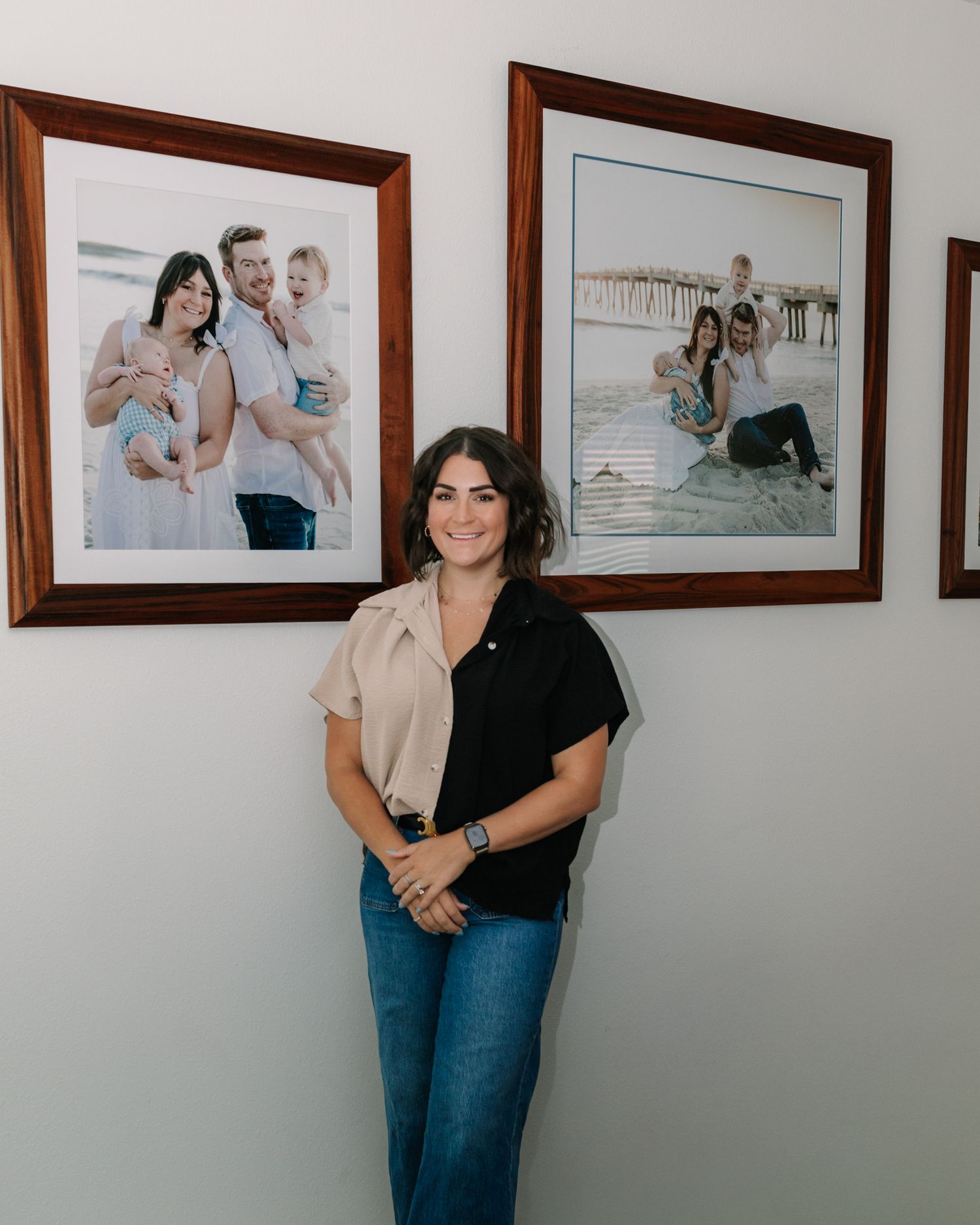 Caitlin standing in front of her framed family portraits