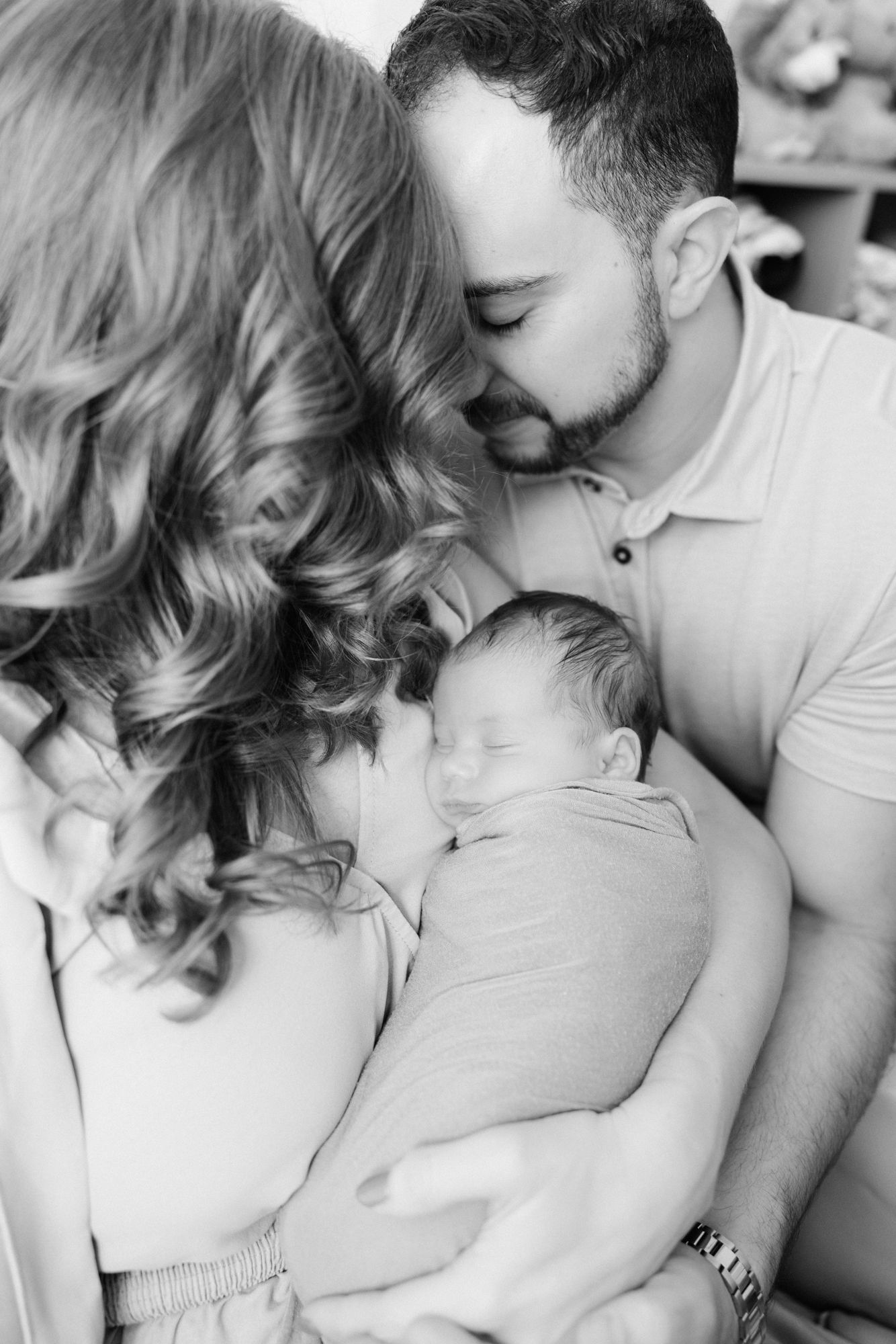 black and white of parents snuggling newborn baby