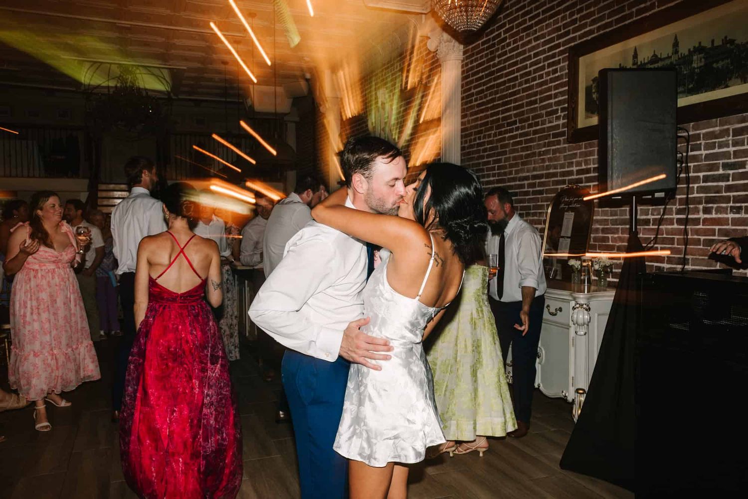 bride and groom kissing at reception with lights behind them