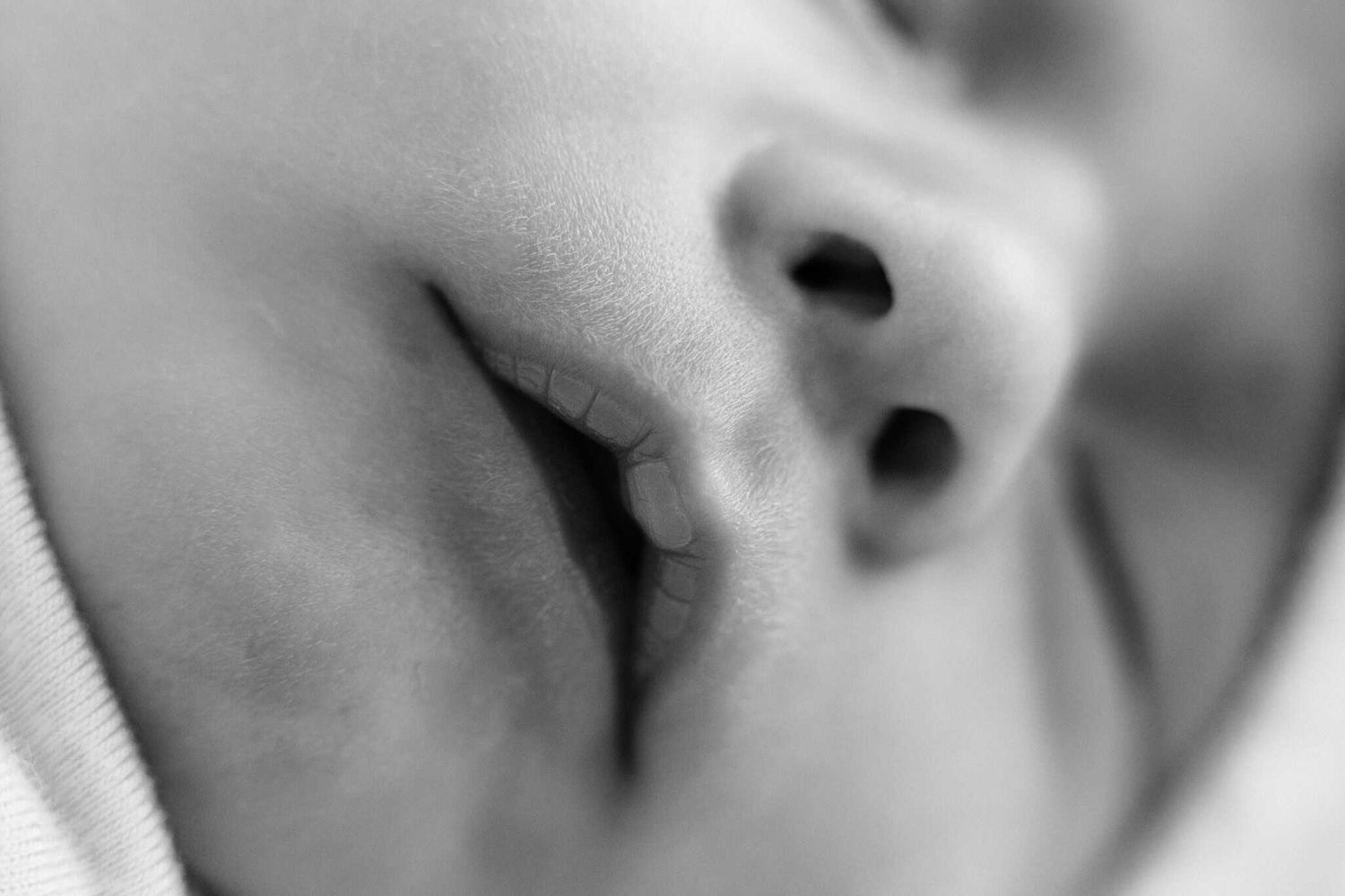 Close-up black and white macro photo of a sleeping newborn baby's nose and lips.
