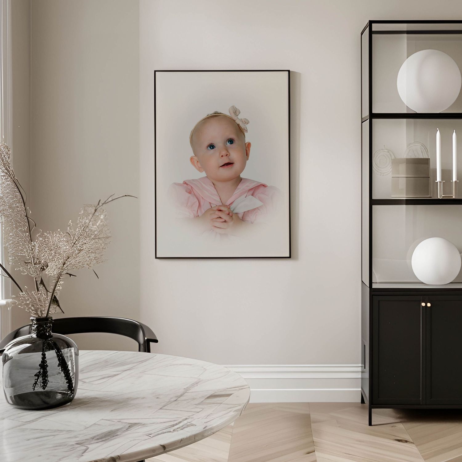 A framed baby portrait in pink hangs on a beige wall above a marble dining table in a modern Scandinavian-style room.