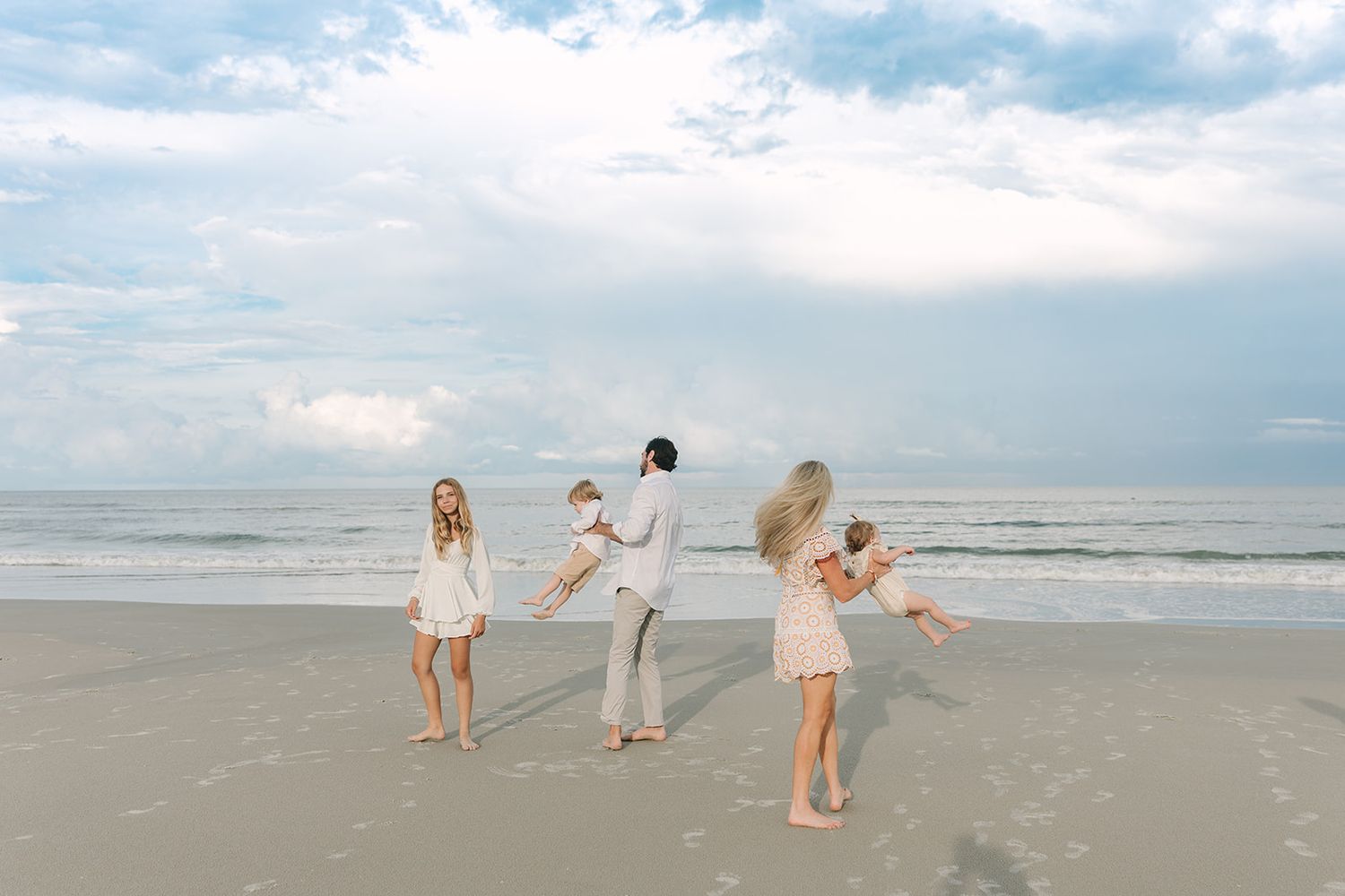 family of five twirling on the Jacksonville beach at sunset wearing all white