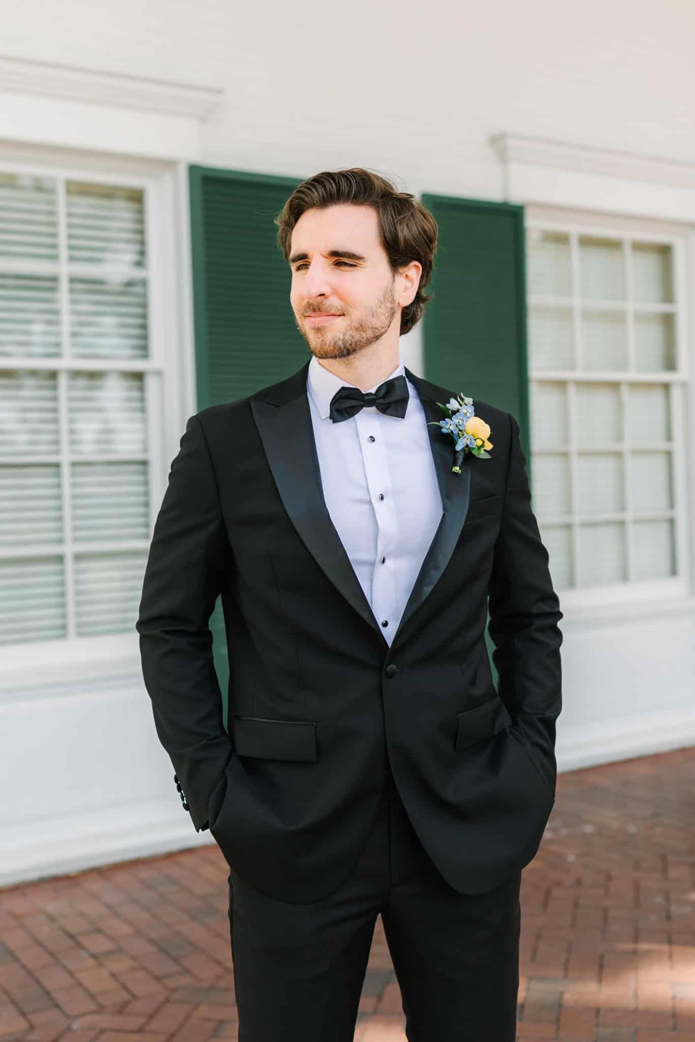 groom standing outside timuquana country club with hands in his pockets looking to the left