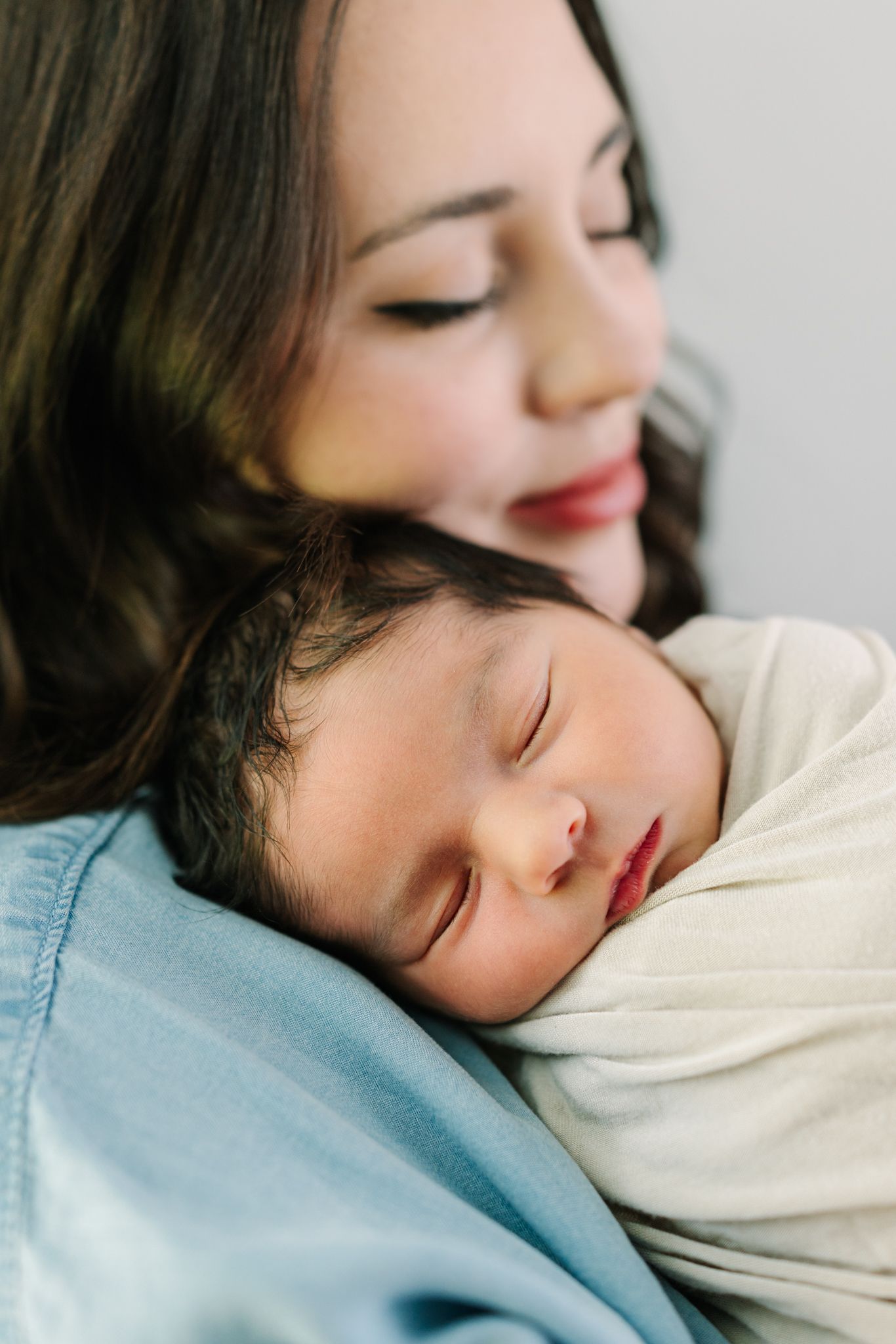 sleeping newborn baby on mom's shoulder while she softly smiles