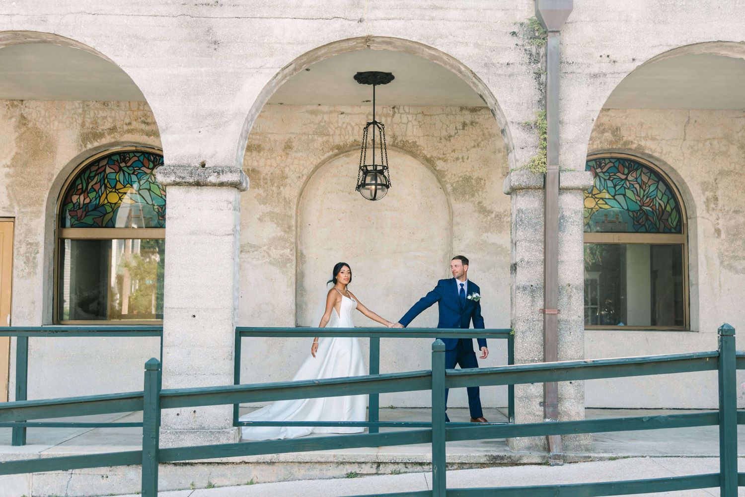 groom leading bride down the hallway under a big arch