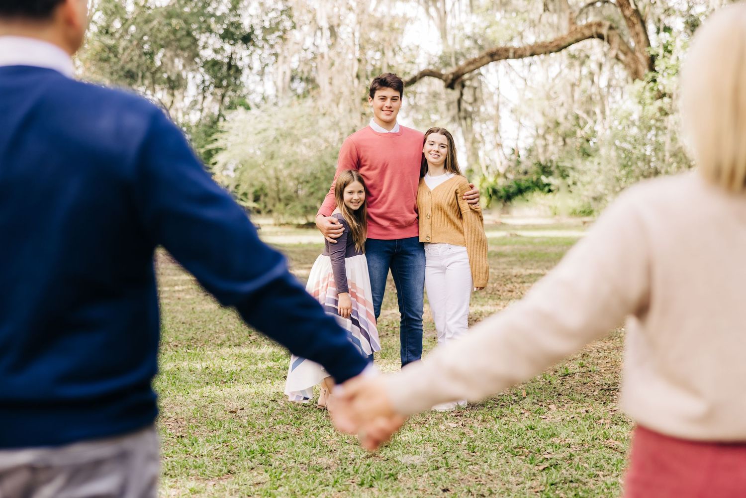 three siblings giving a hug while mom and dad hold hands in front of them