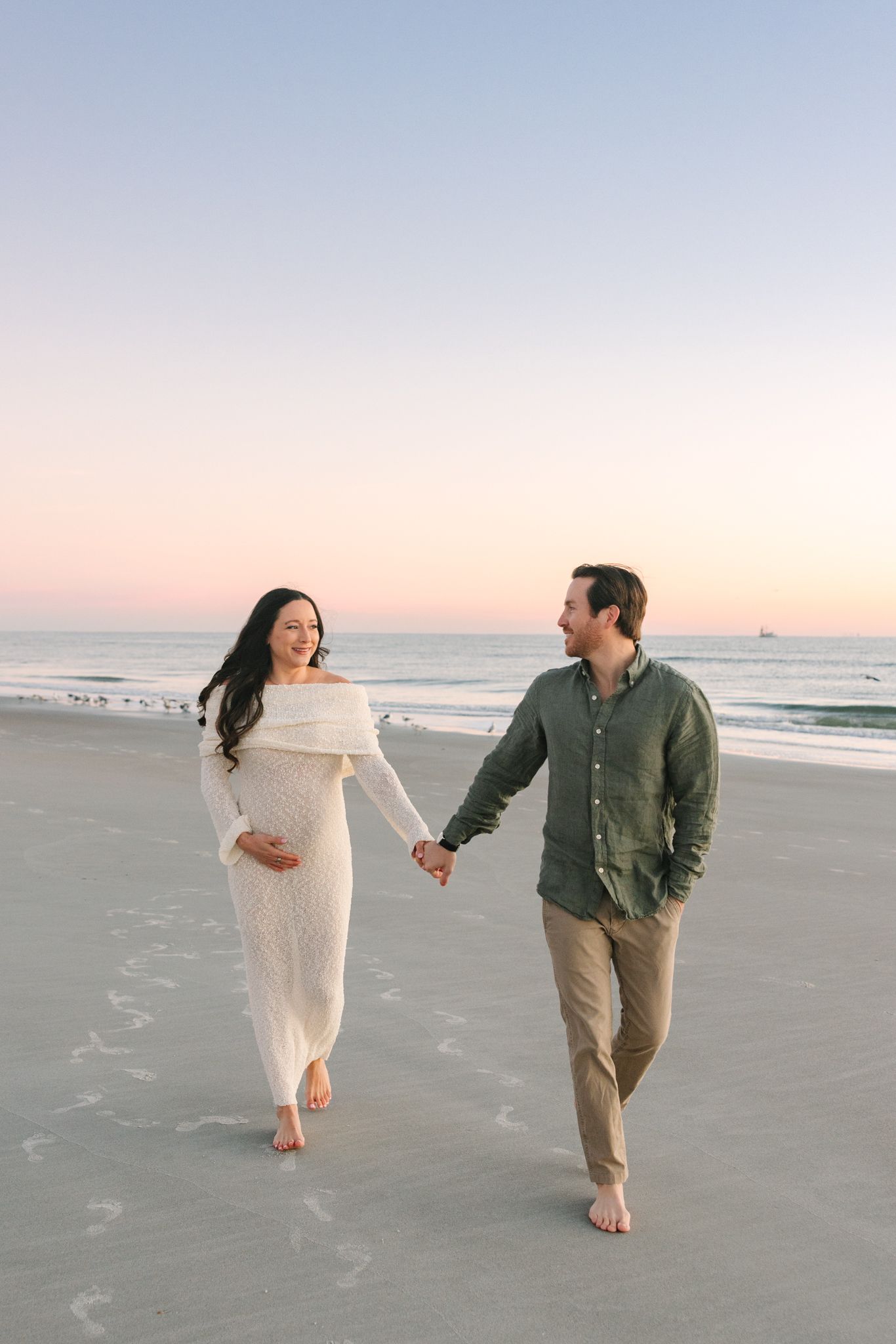dad leading pregnant wife down Jacksonville beach, fl at sunrise