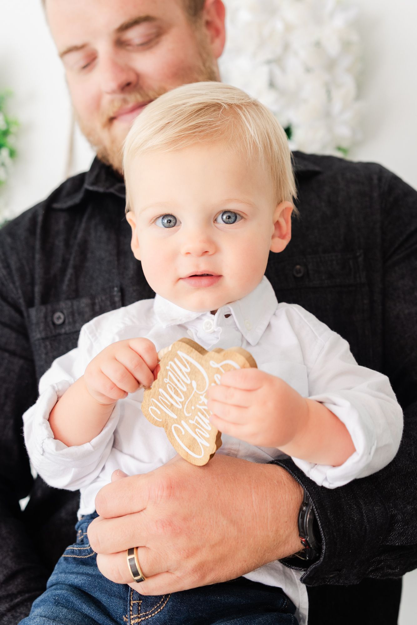 adorable blonde son holding merry Christmas ornament