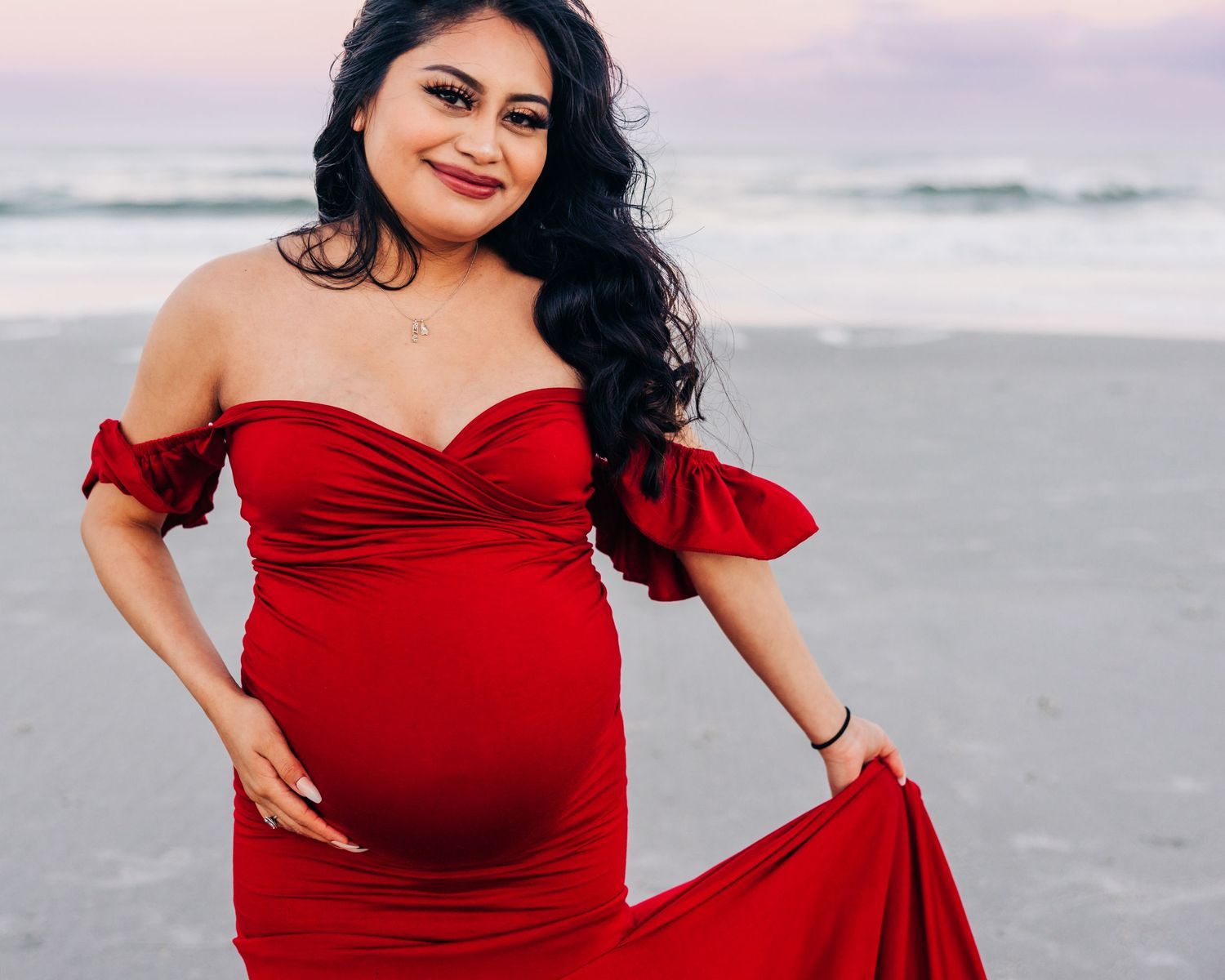 pregnant woman on the beach at sunset with pretty red dress