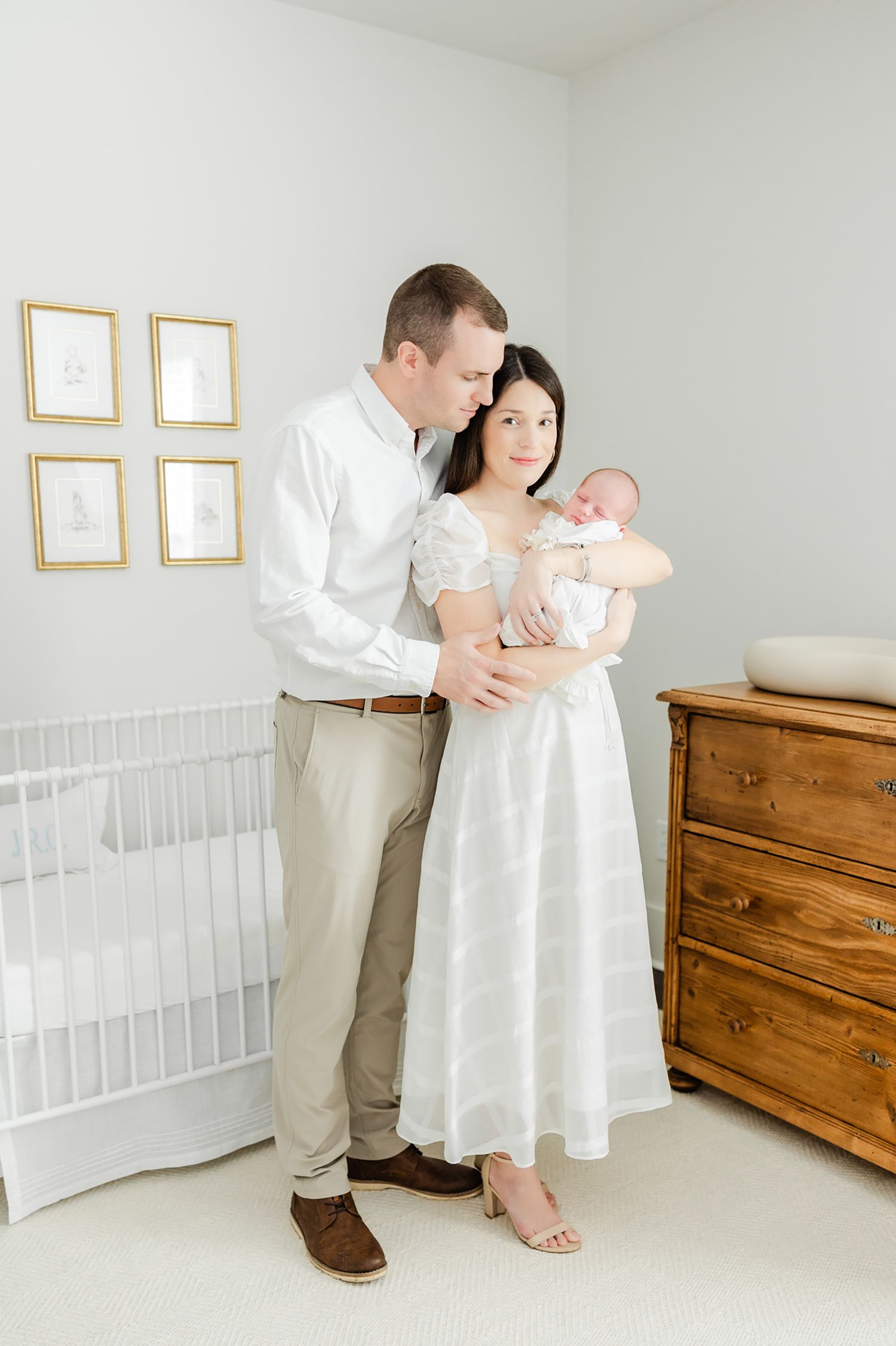 mom and dad holding newborn baby in the nursery