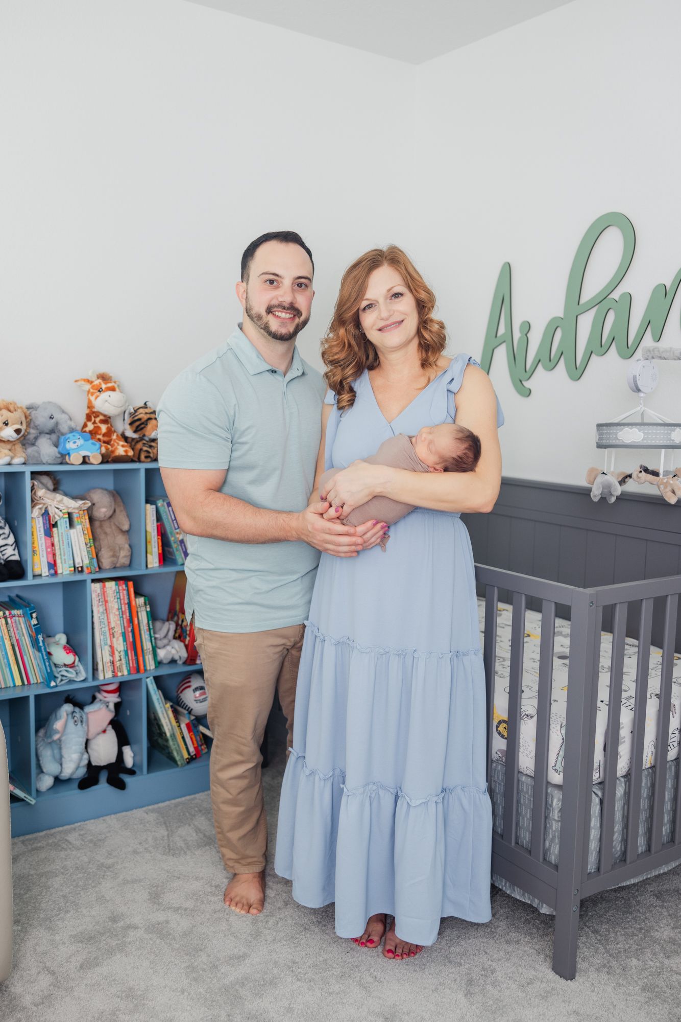 parents holding newborn baby in the nursery in front of his crib