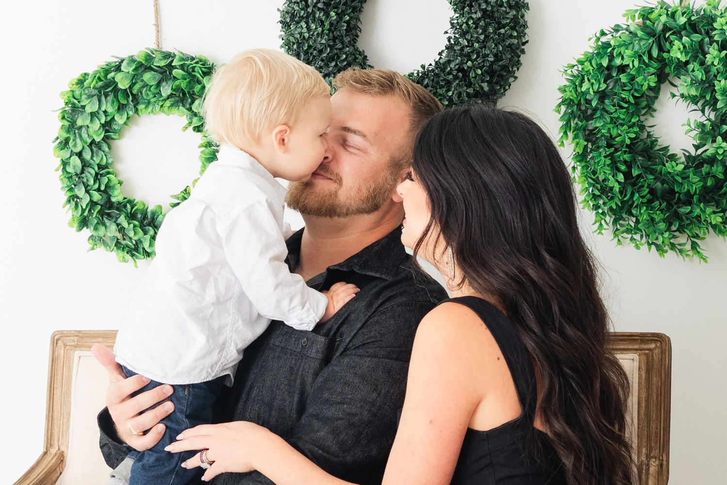 family snuggles and kisses at Christmas session with wreaths