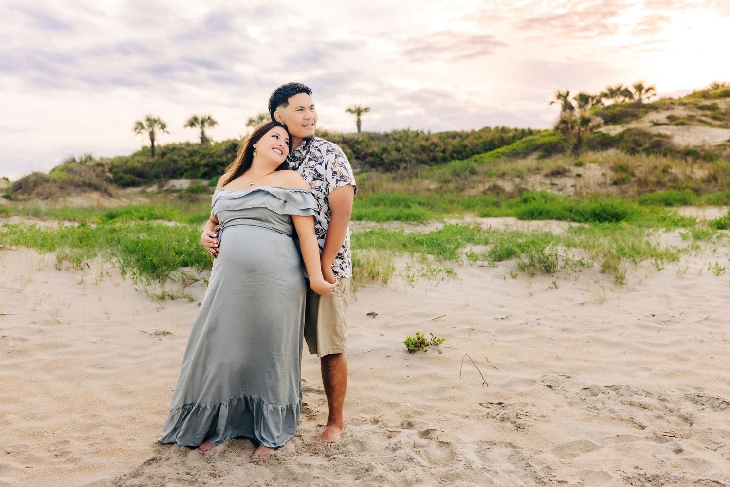 pregnant couple leaning into eachother at sunset