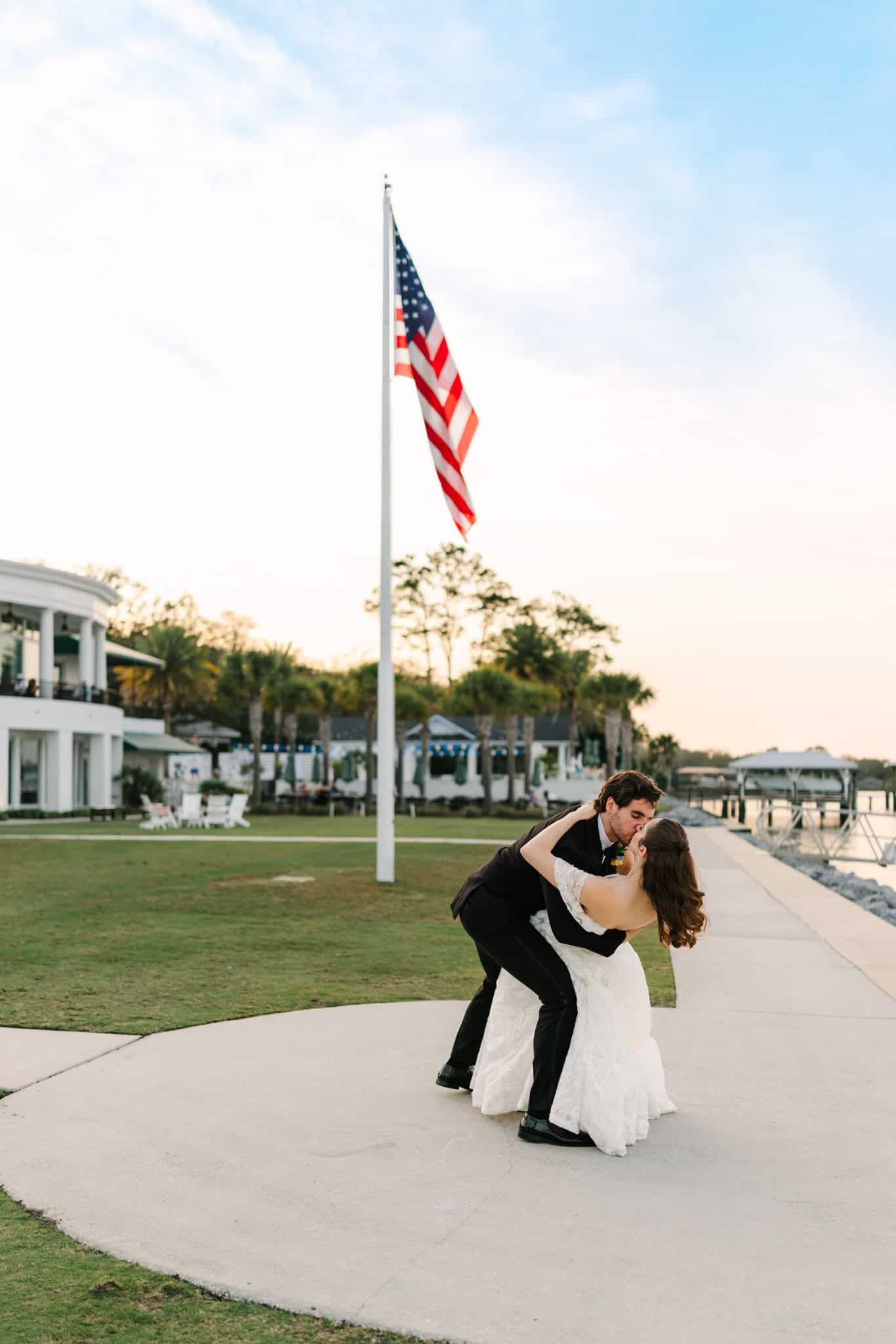 groom dipping bride with an american flag behind them