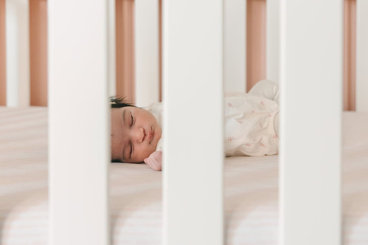 newborn baby in Jacksonville fl laying in crib, peeking in from outside the crib
