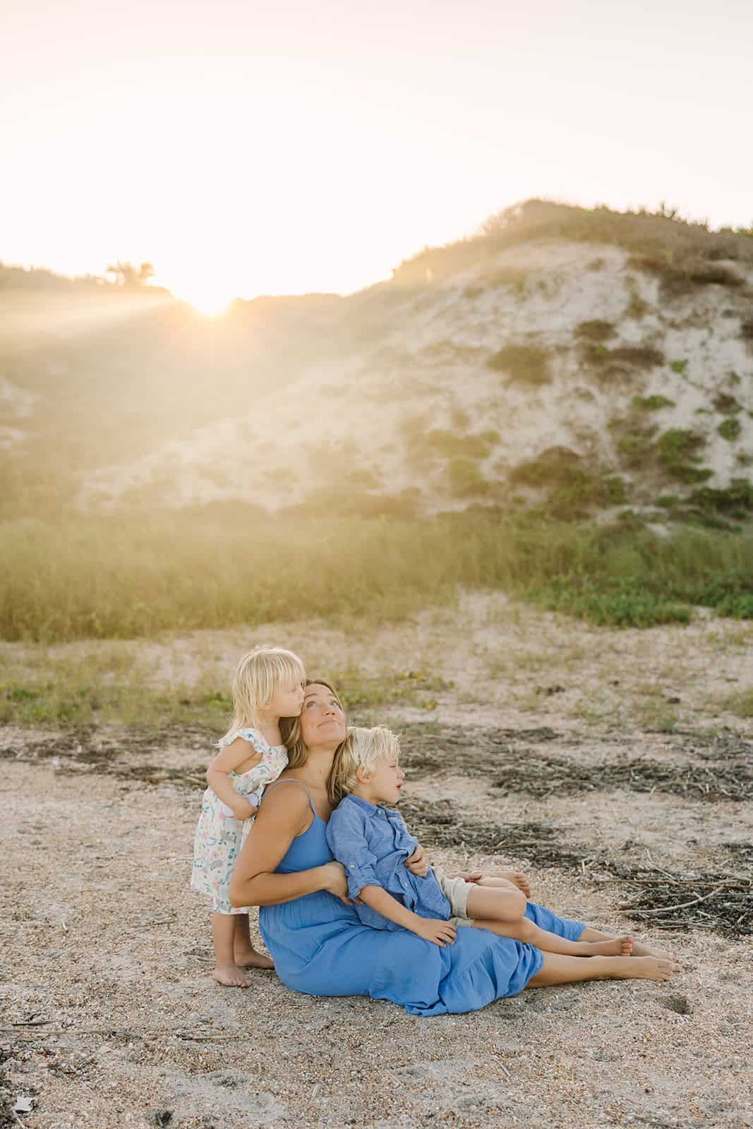 sunset over the Ponte Vedra Beach dunes with mom sitting in the sand snuggling with her two toddlers
