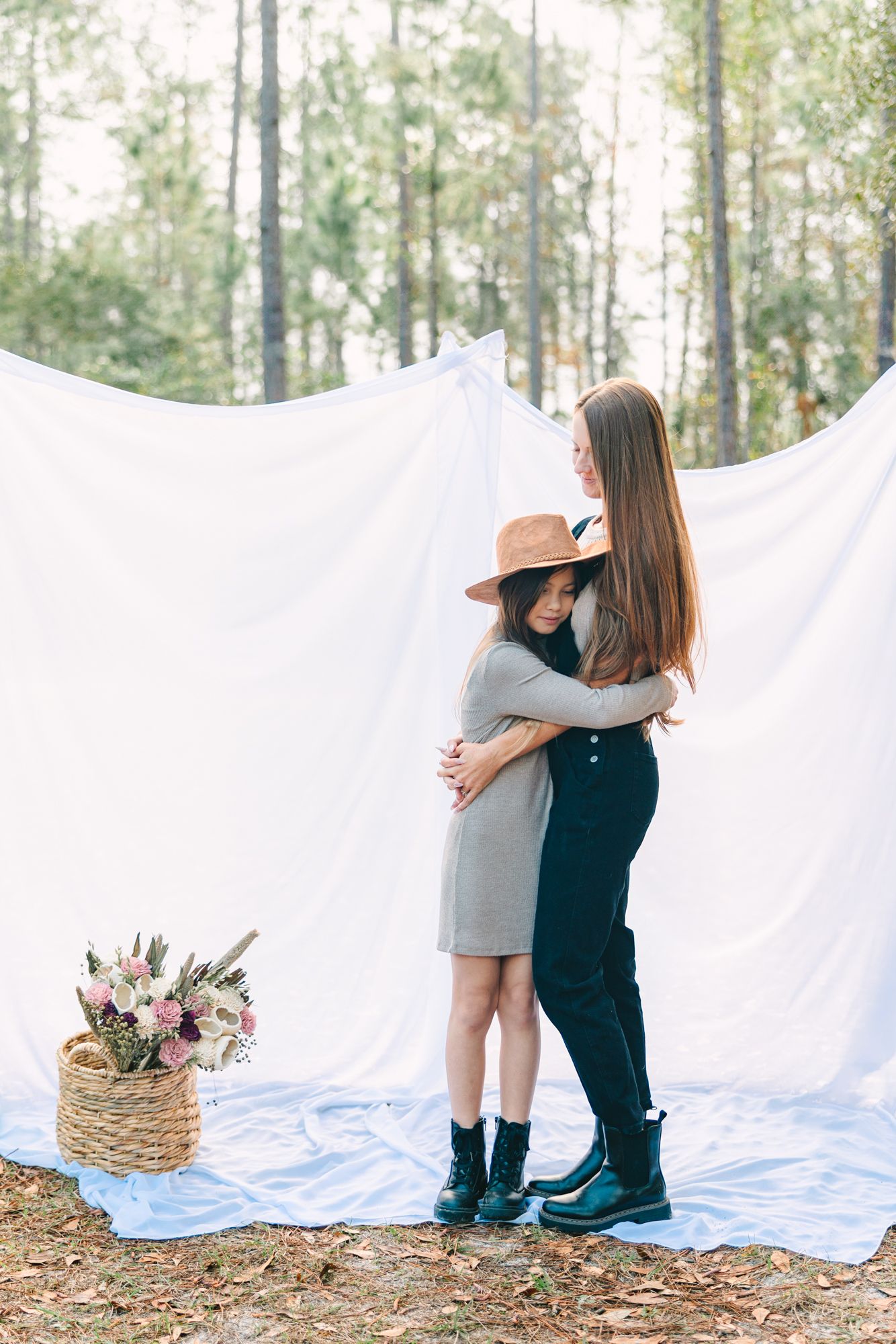 mom and daughter hugging outside with sheet hanging