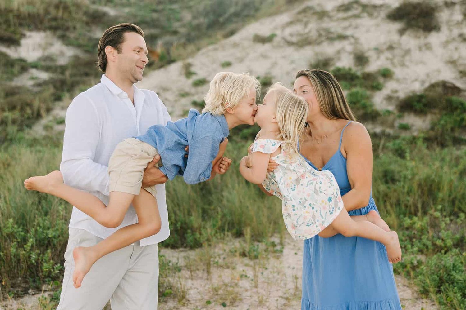 mom and dad air planing toddlers to give a kiss at the beach in Jacksonville fl