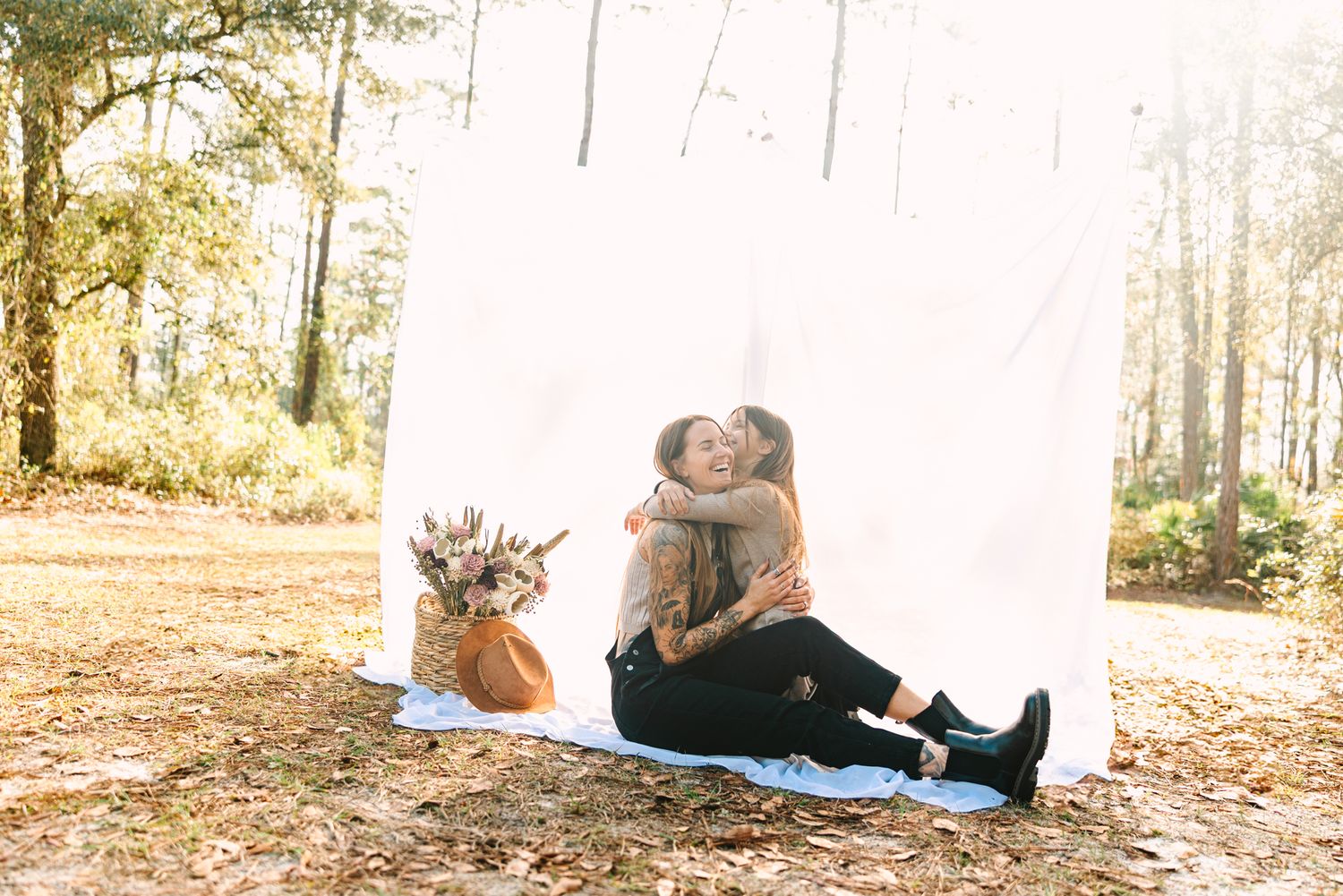 mom and daughter hugging outside with sheet hanging they are sitting