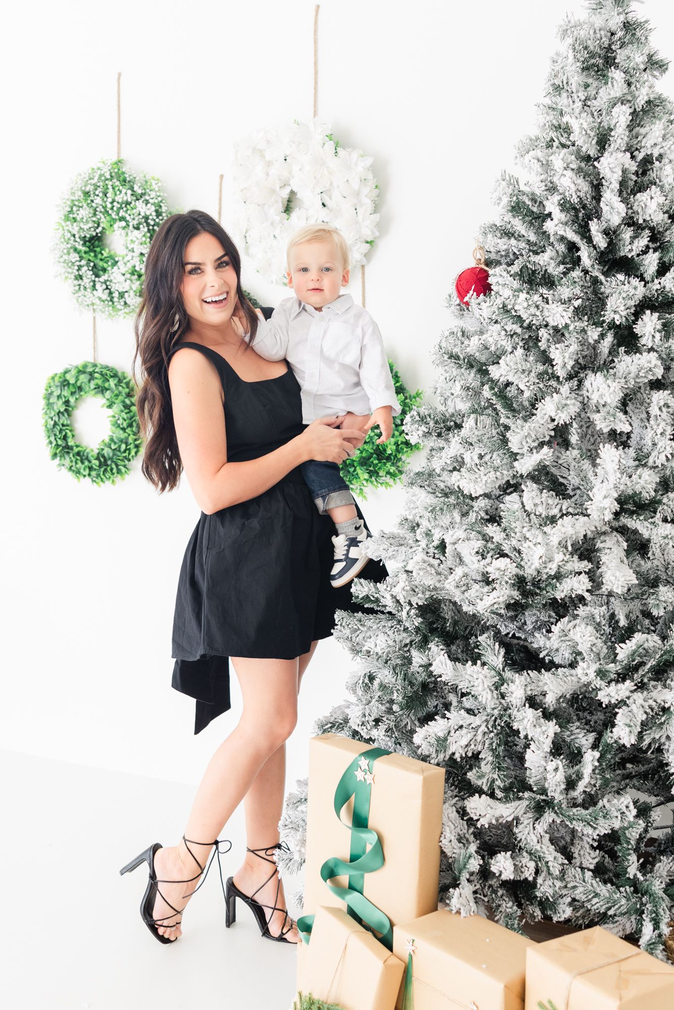 mom holding son laughing in front of Christmas tree