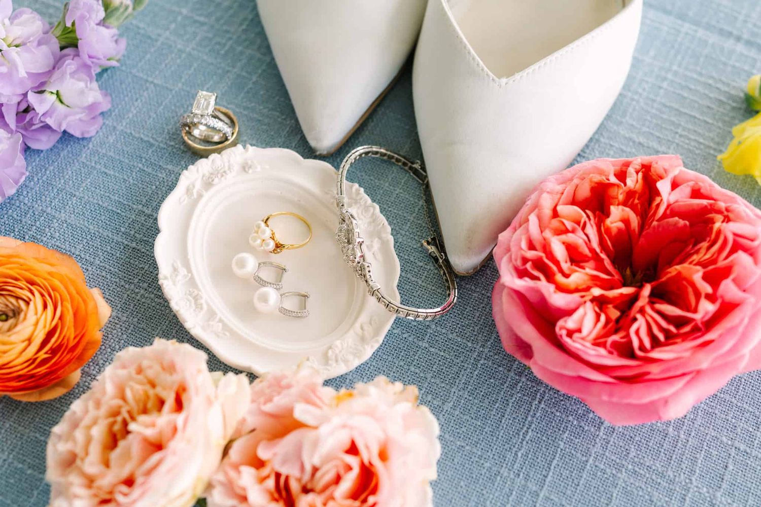 flat lay of bridal jewelry shoes and flowers