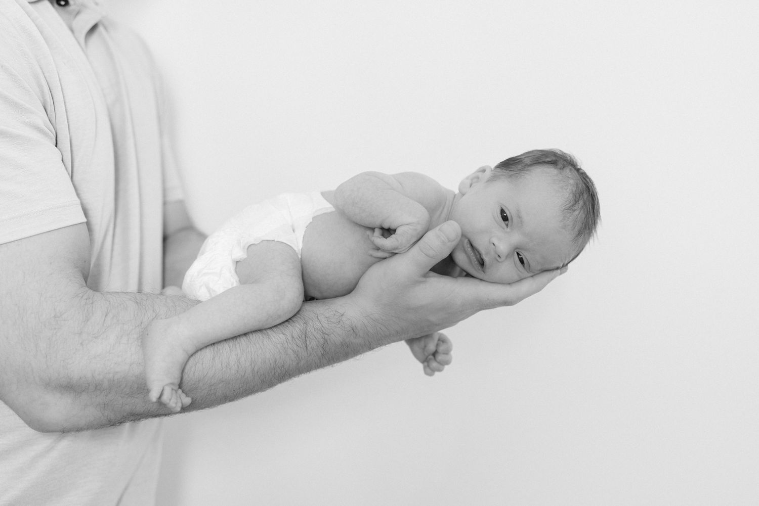 newborn baby in black and white laying on dads arm