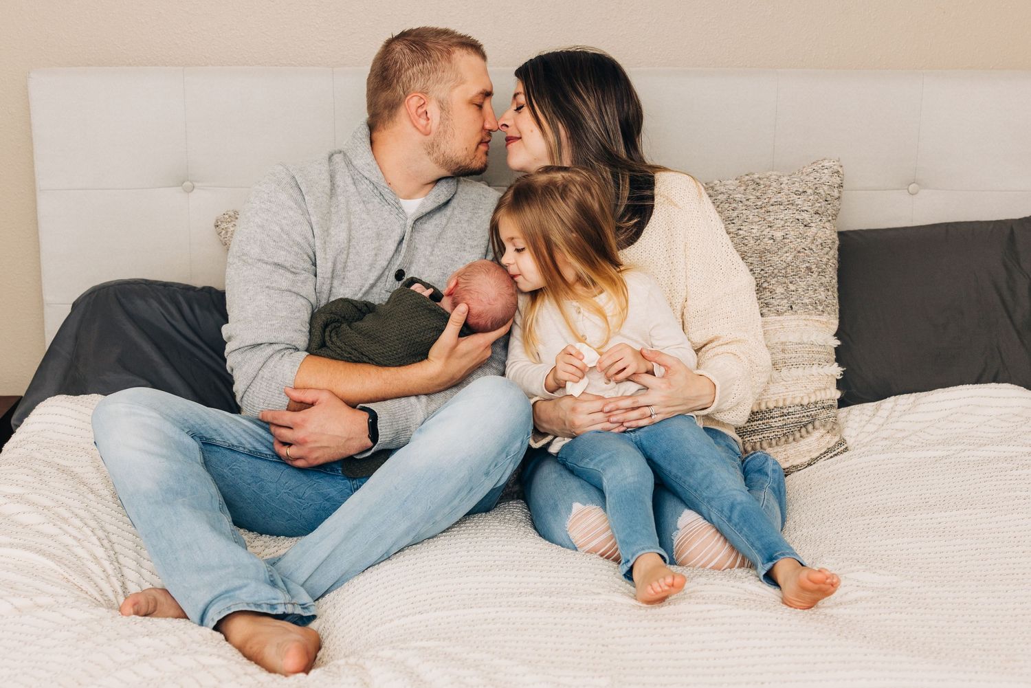 family snuggling on bed during newborn session