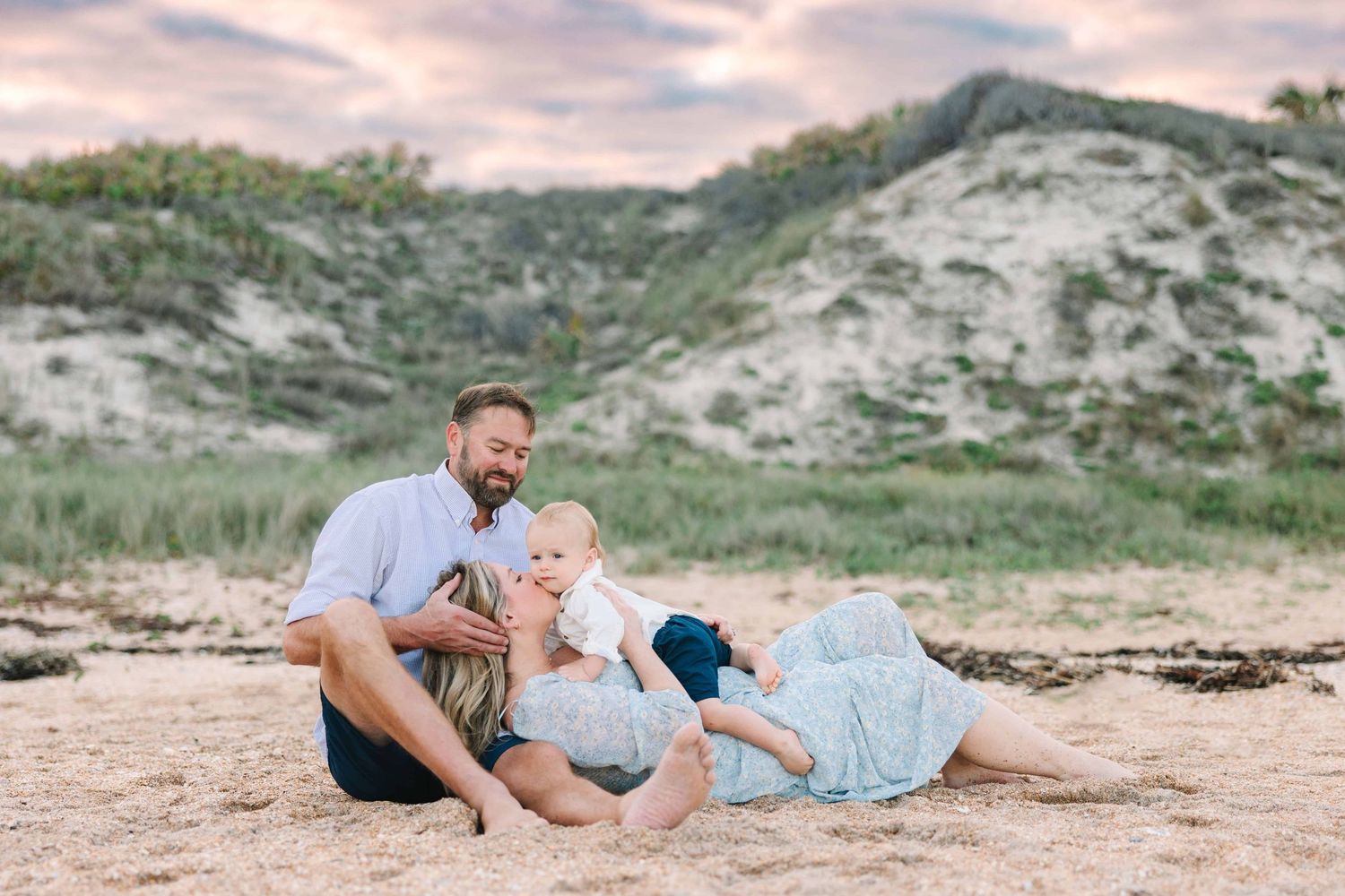 family on the beach for Christmas cards in Ponte vedra beach fl mom laying and kissing her son at sunset