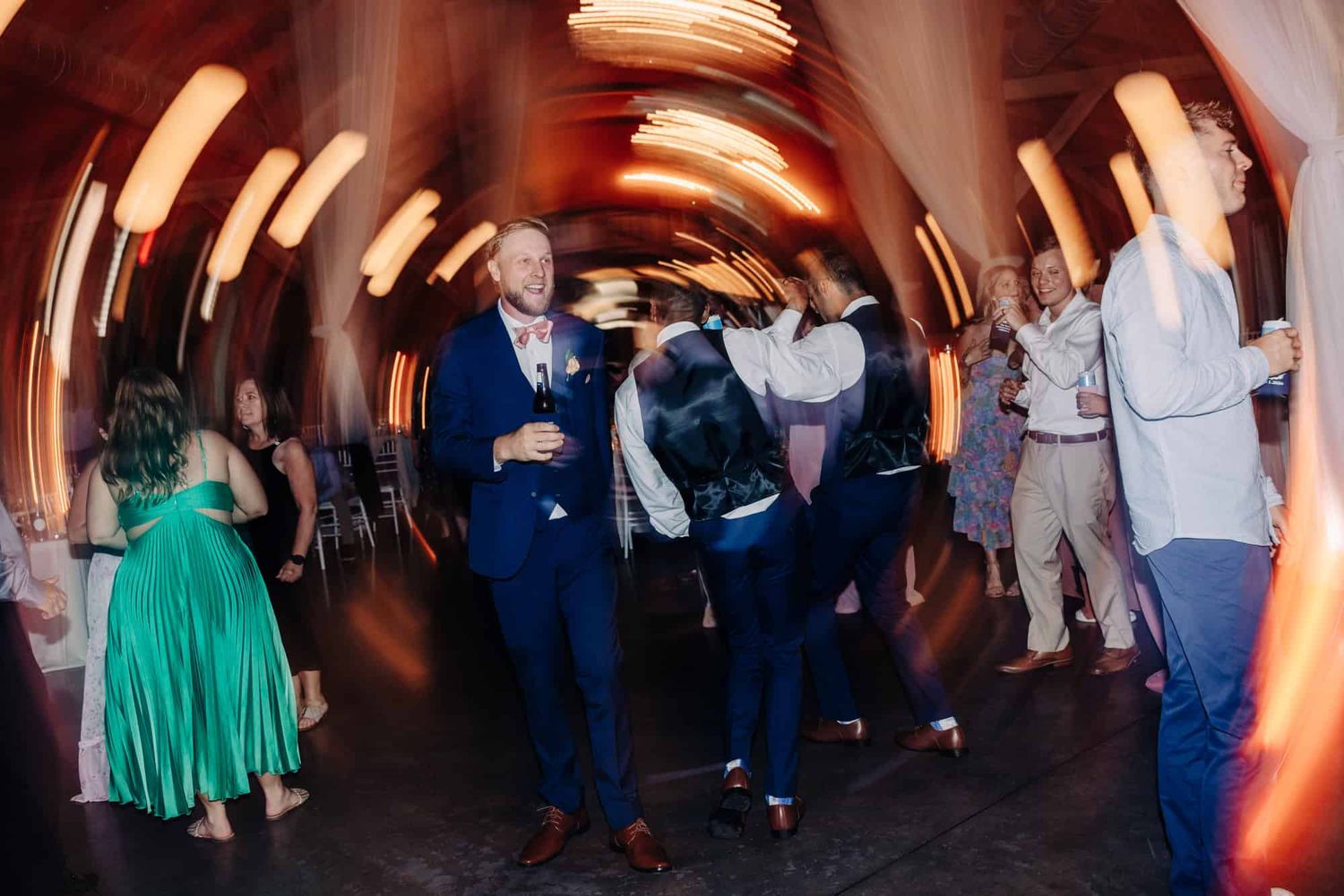 motion blur of people dancing at wedding reception lights circling around them