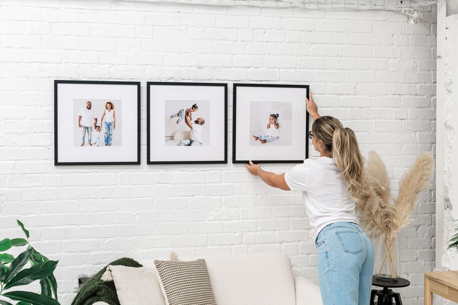 woman hanging three frames of family photos taken by Jacksonville, fl photographer