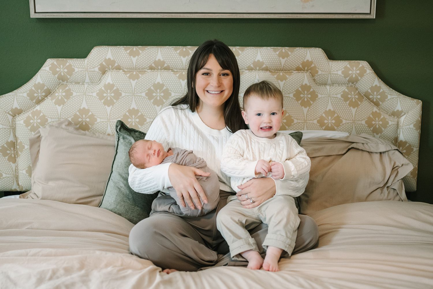 Caitlin holding both of her sons sitting on her bed