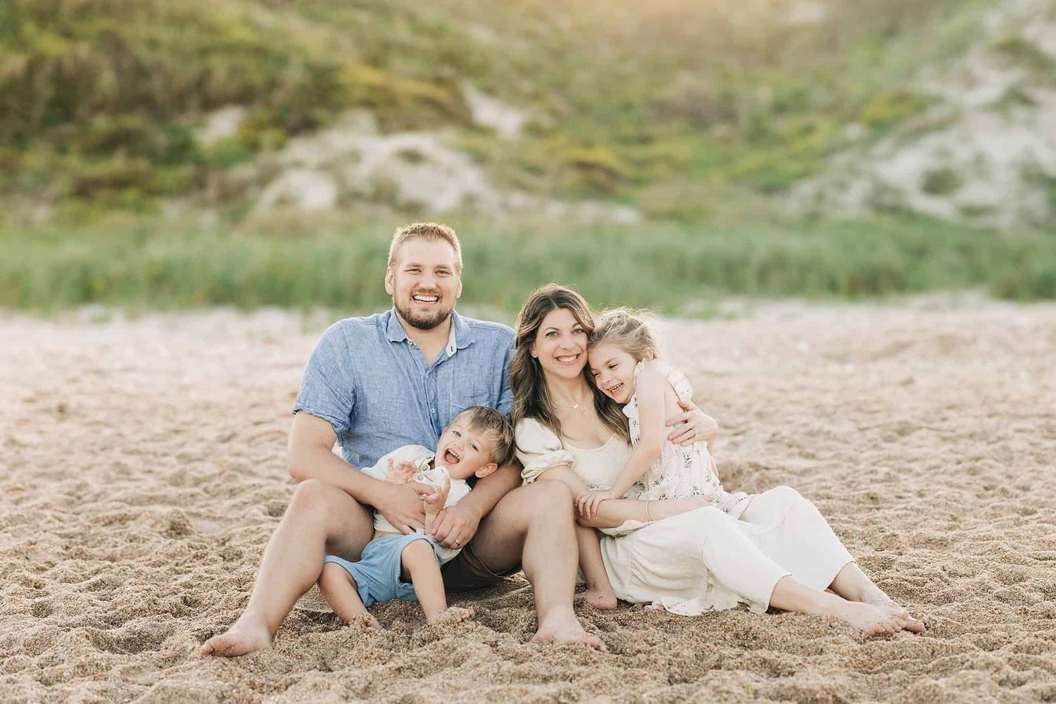family sitting on the beach in front of the dunes in Ponte Vedra Beach fl. mom, dad, son, and daughter
