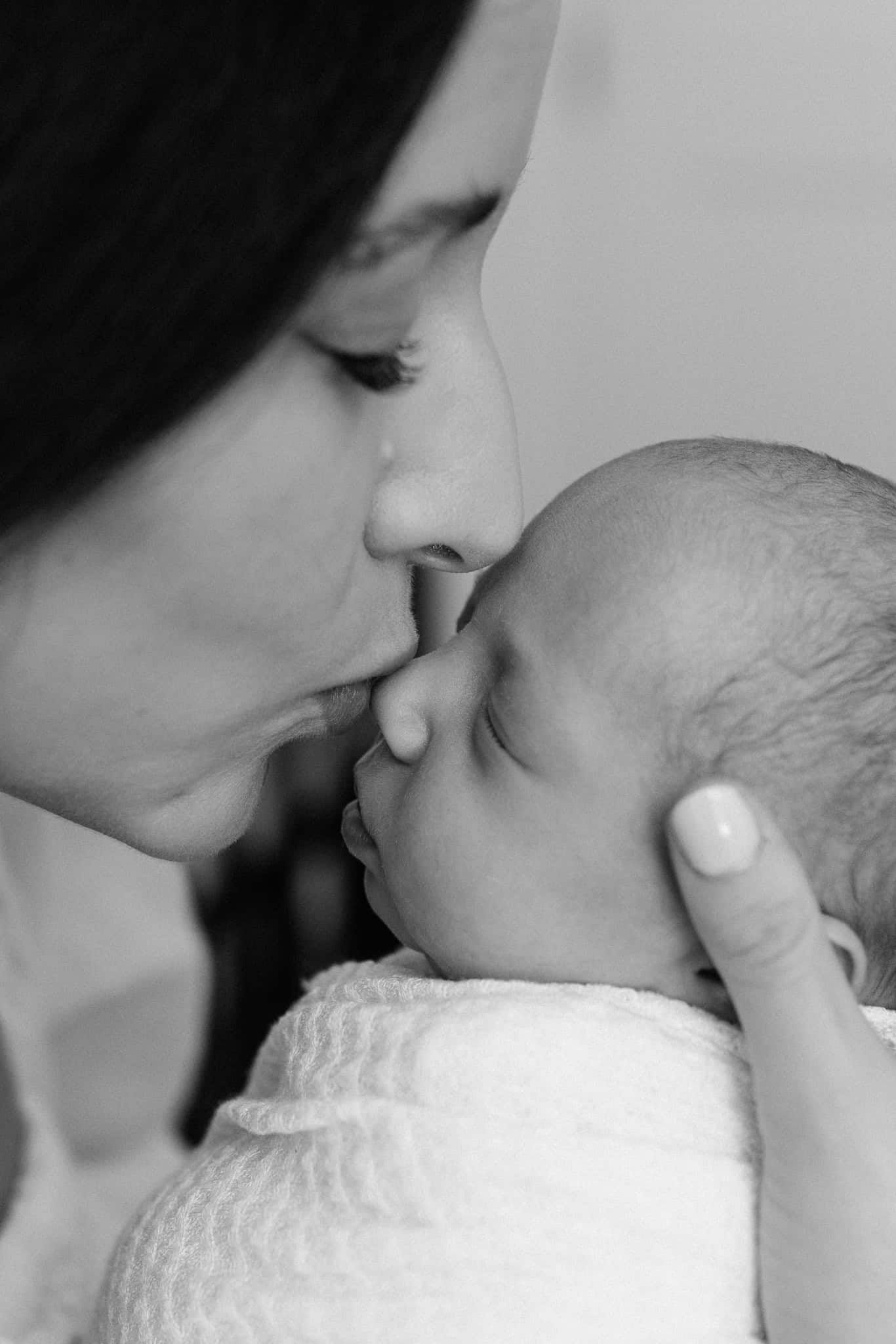 mom kissing newborn baby girl's nose in black and white