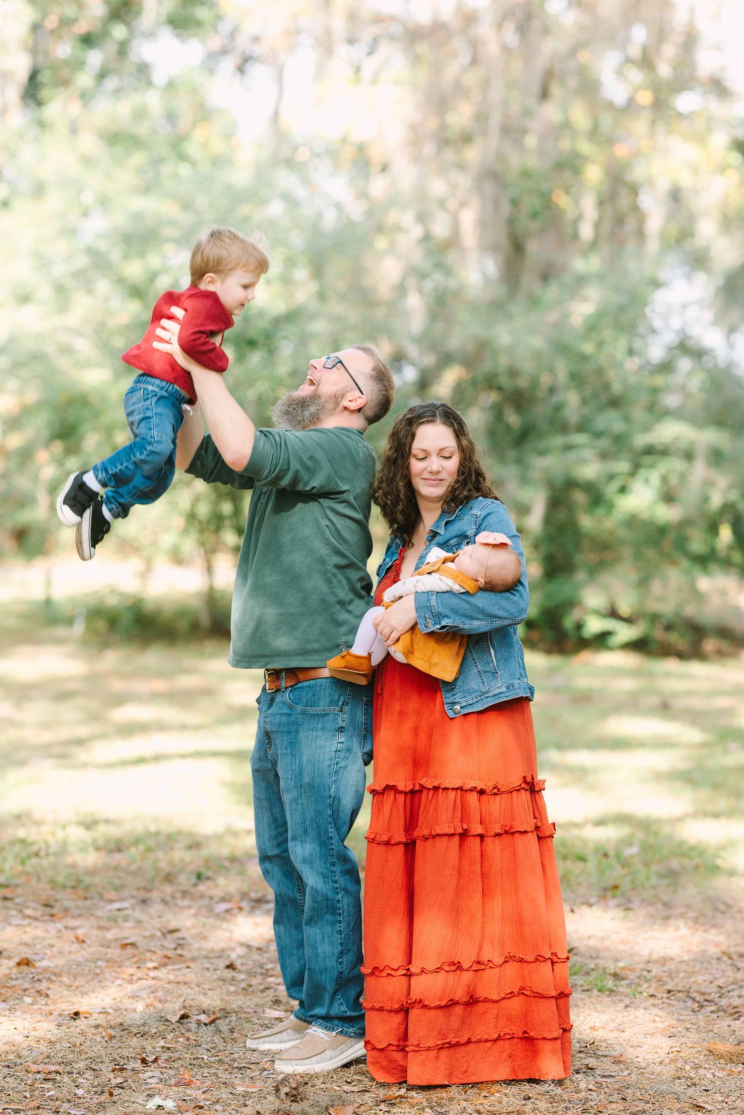 mom snuggling new baby and dad throwing toddler boy in the air at Walter Jones park in mandarin in Jacksonville, fl