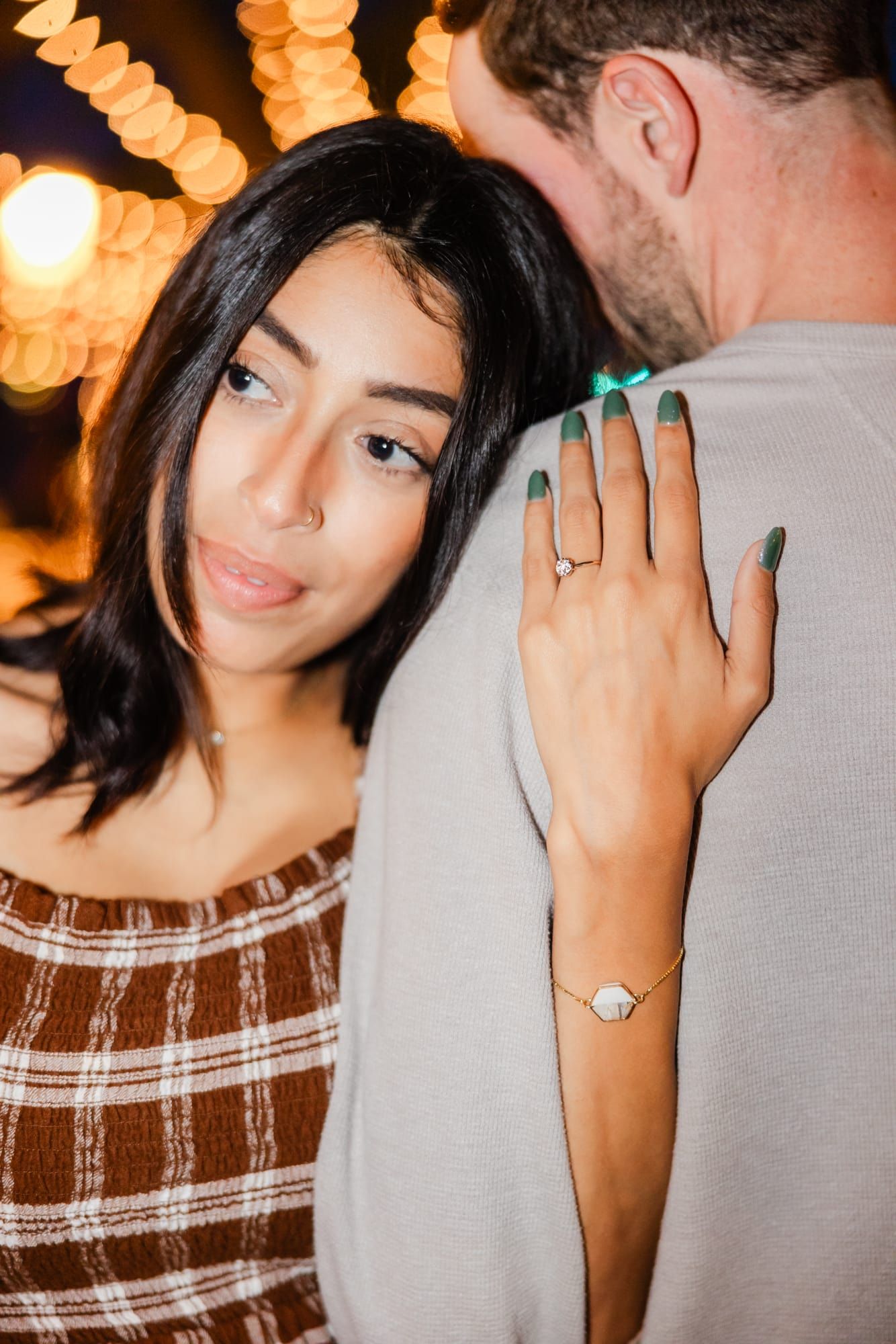woman leaning on her fiancé's shoulder with engagement ring showing and her hand on his shoulder