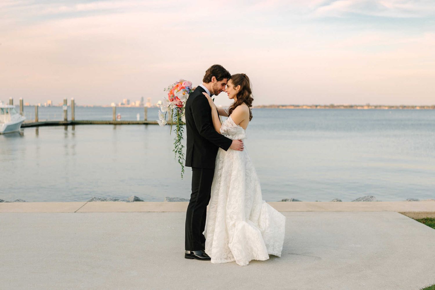bride and groom hugging during sunset in front of the water