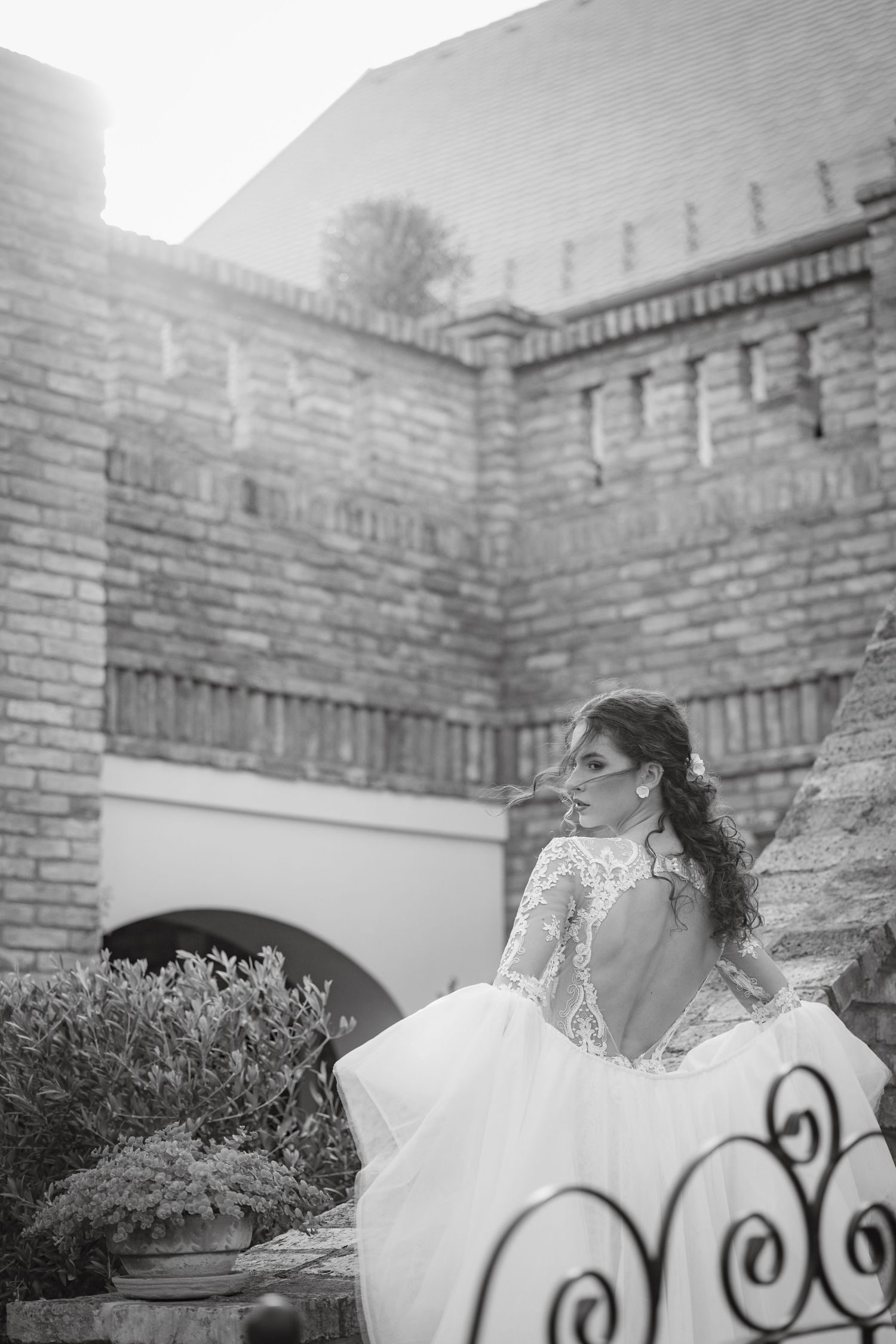 Elegant bridal portrait against rustic brick wall with vintage ironwork details.