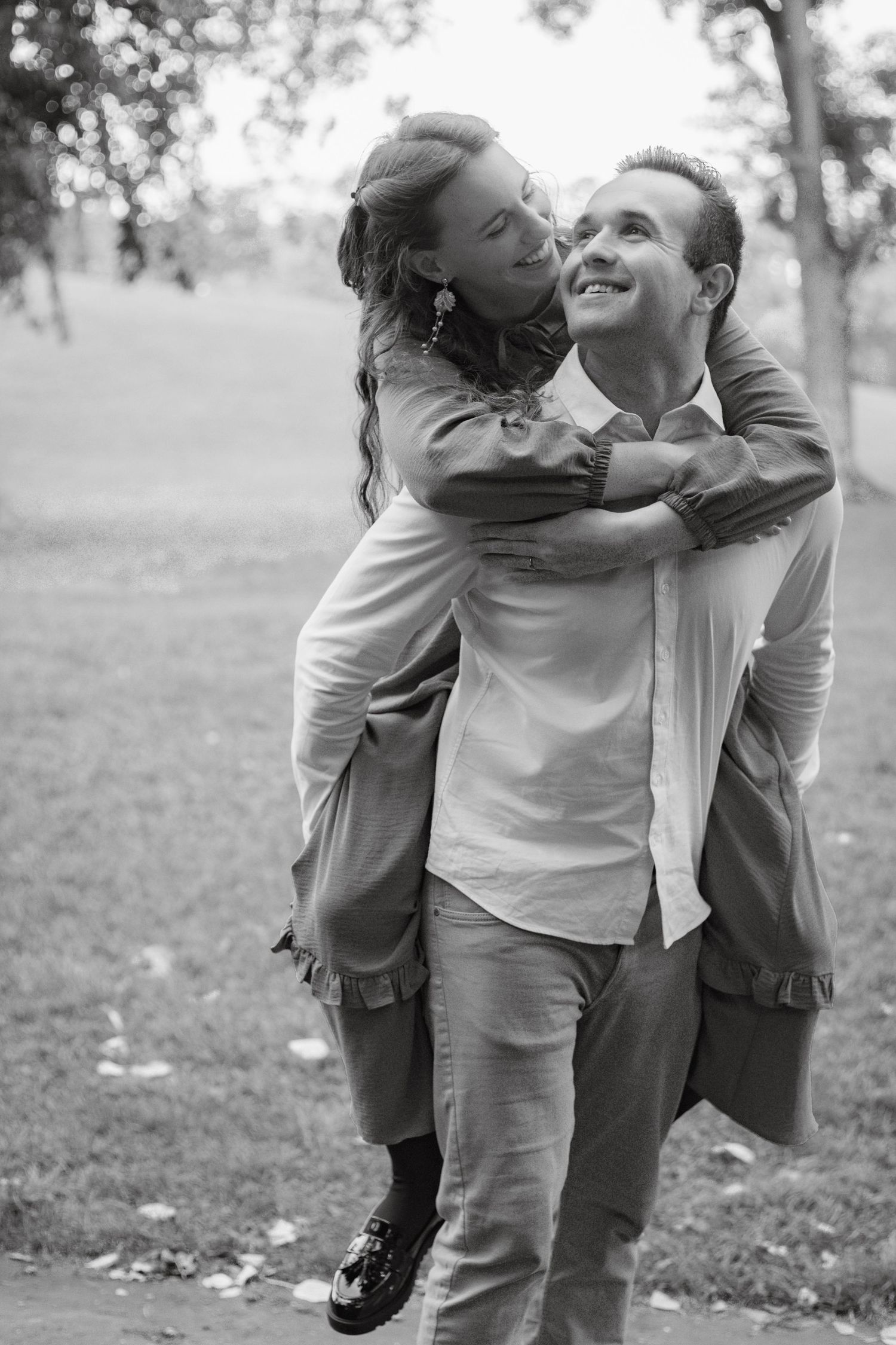 Playful moment shared between two people in casual attire on a grassy field.
