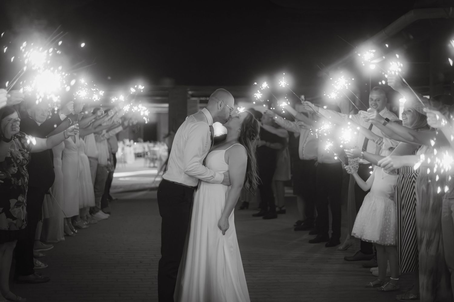 A nighttime wedding exit with guests holding sparklers creating a magical atmosphere.