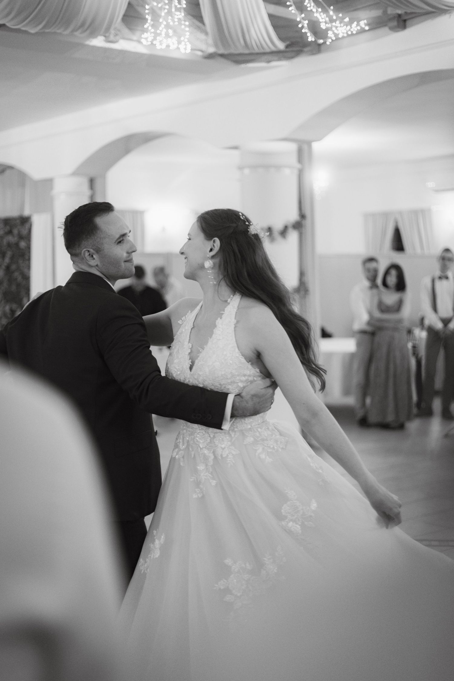 Black and white photo of a bride and groom sharing their first dance at a wedding reception.