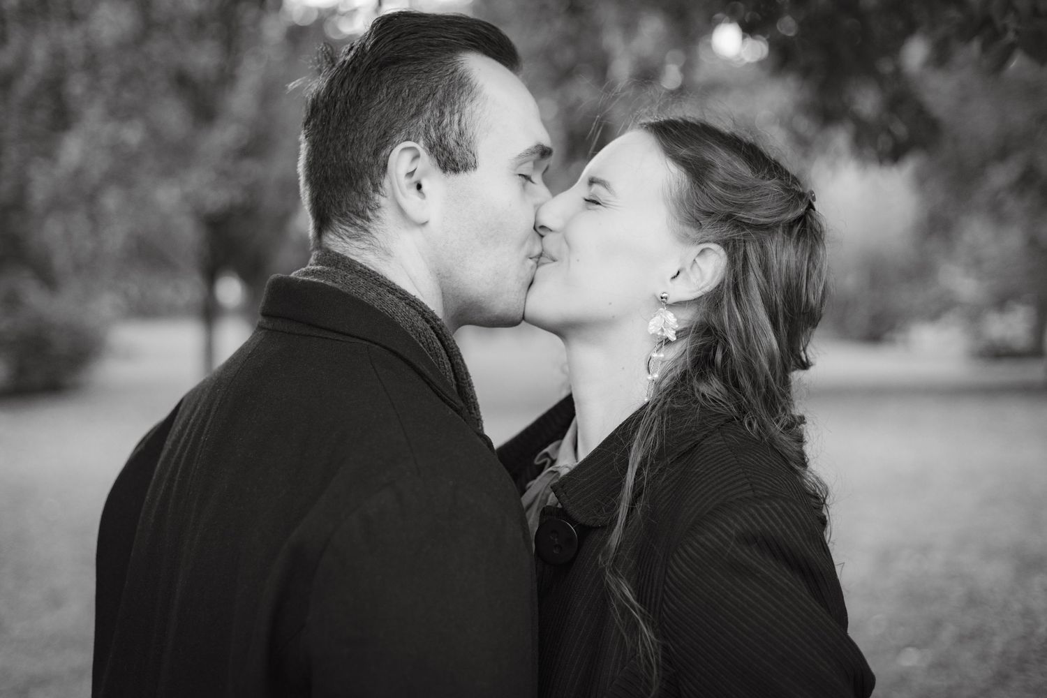 A romantic black and white moment captured between two people in an outdoor setting.