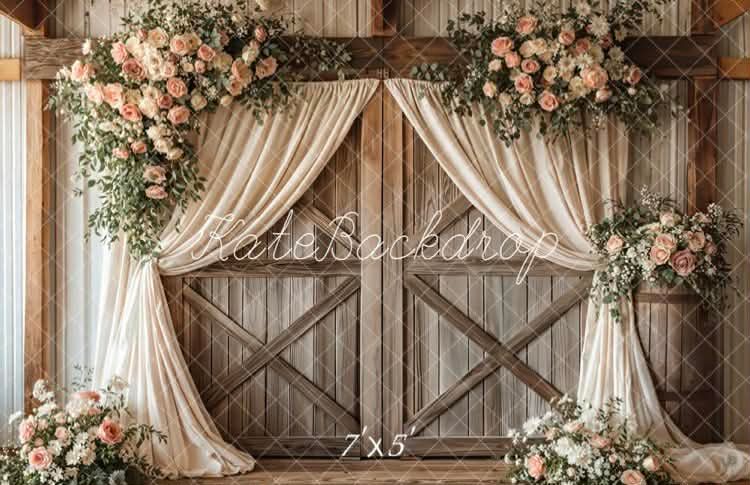 Rustic wooden barn doors decorated with elegant cream drapes and pink floral arrangements for a romantic wedding backdrop.