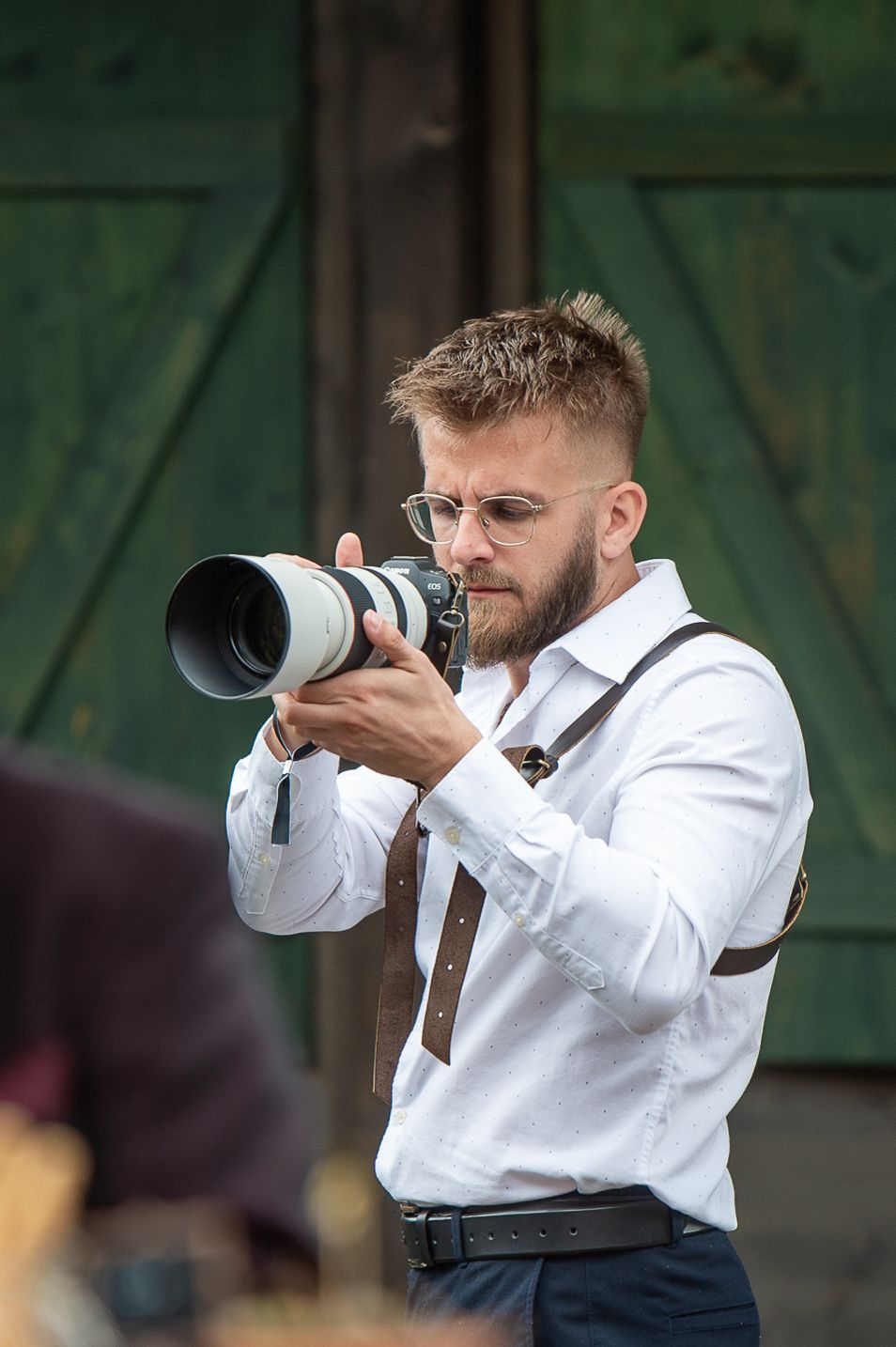 Professional photographer in formal attire captures shots with a telephoto lens.
