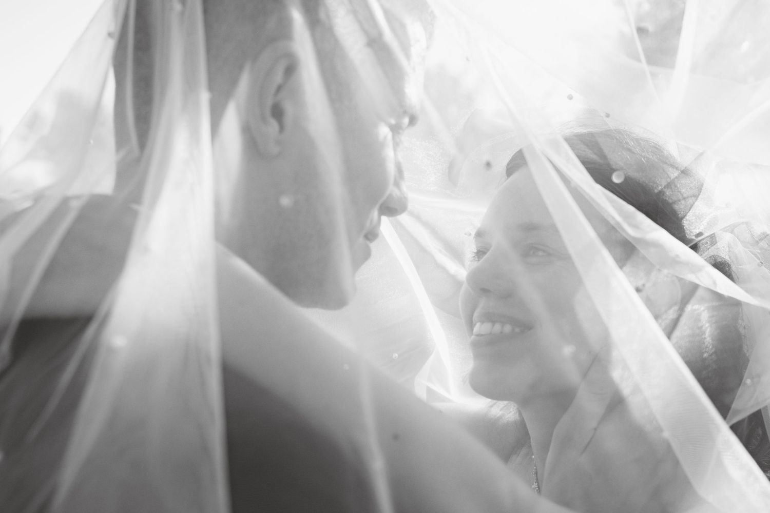 Close-up details of delicate white wedding dress fabric with sunlight filtering through.
