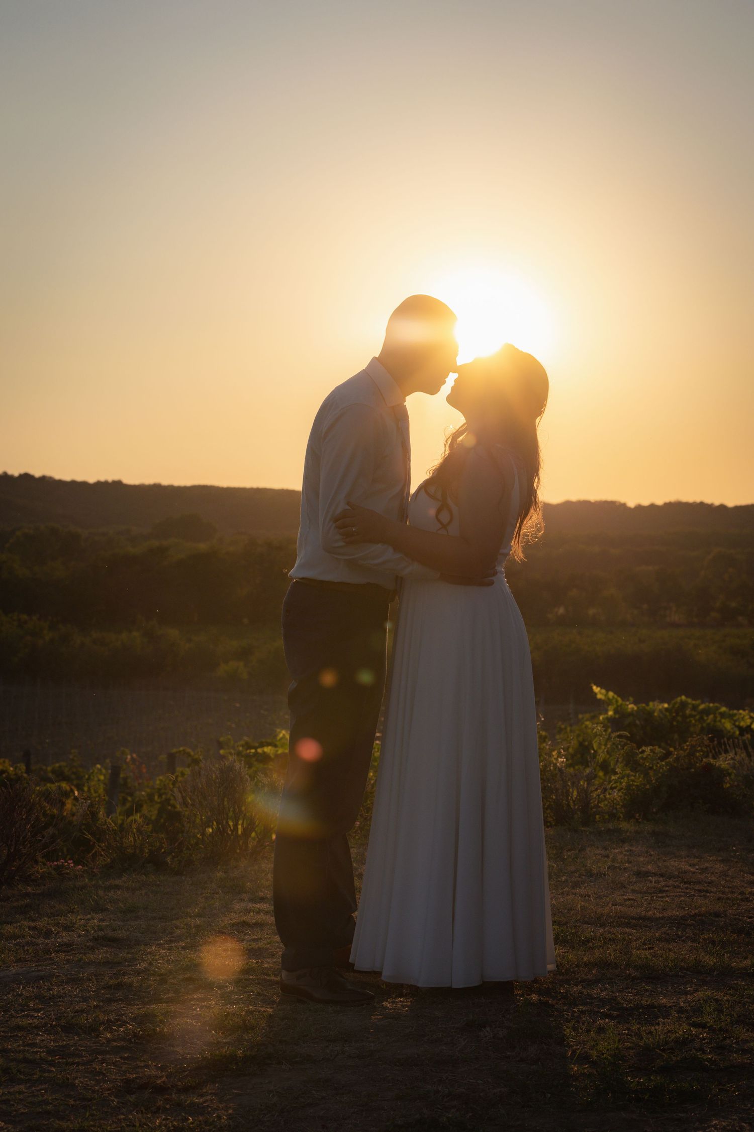 Romantic sunset silhouettes against warm golden sky during outdoor wedding photoshoot.