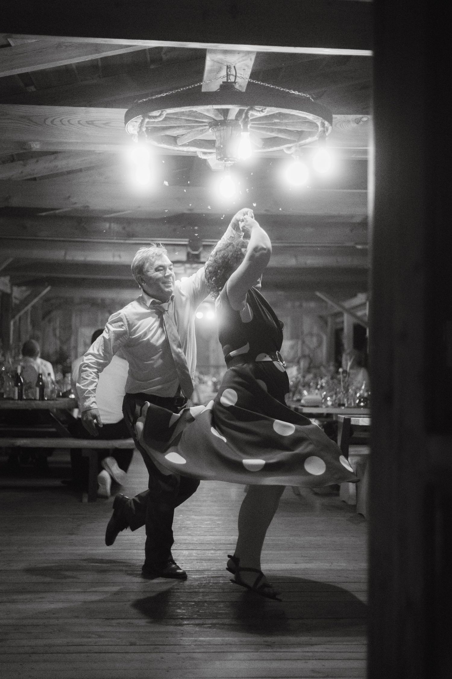 Black and white photo of energetic dance moves during wedding reception.