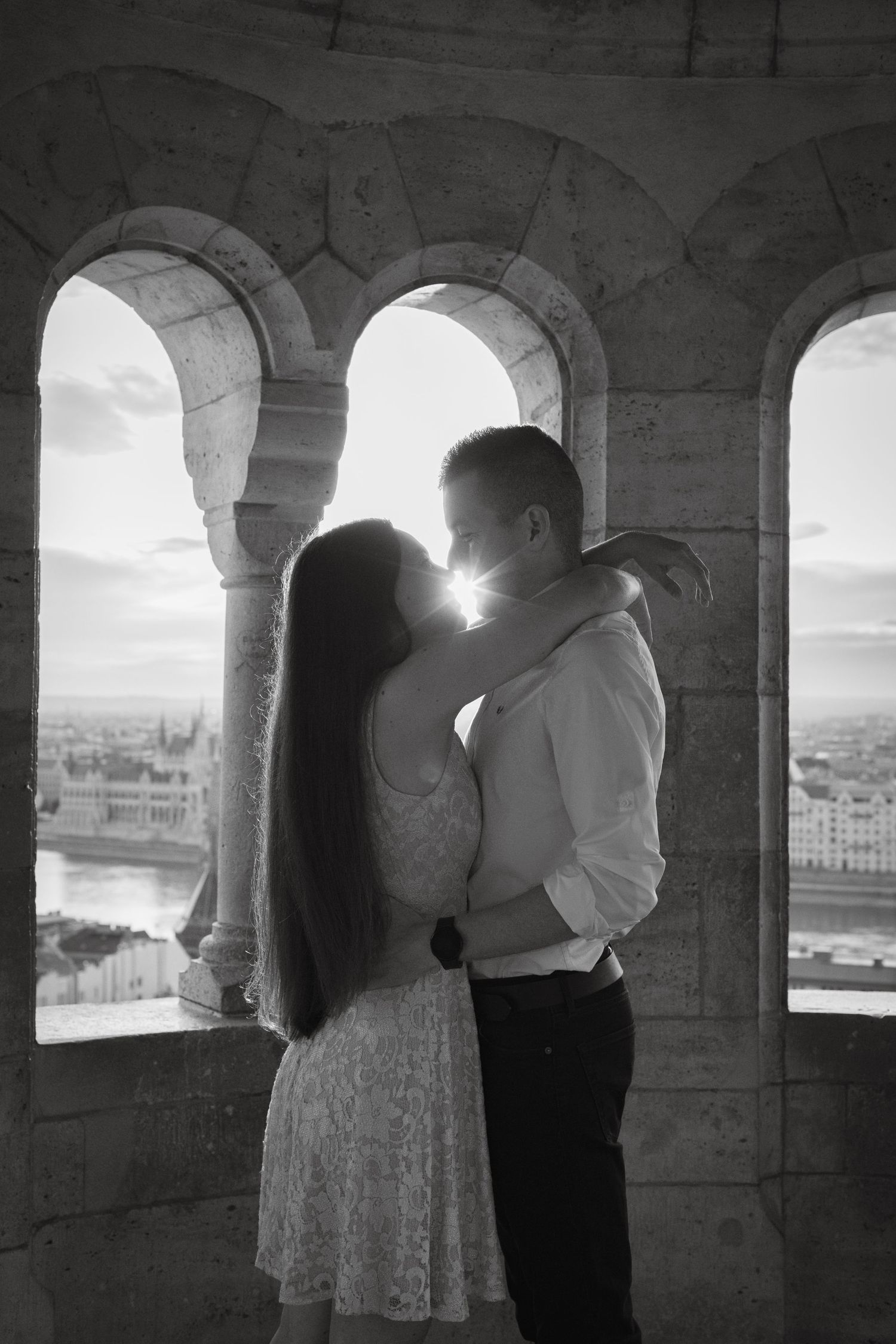 A romantic moment captured through stone archways with a scenic view beyond.