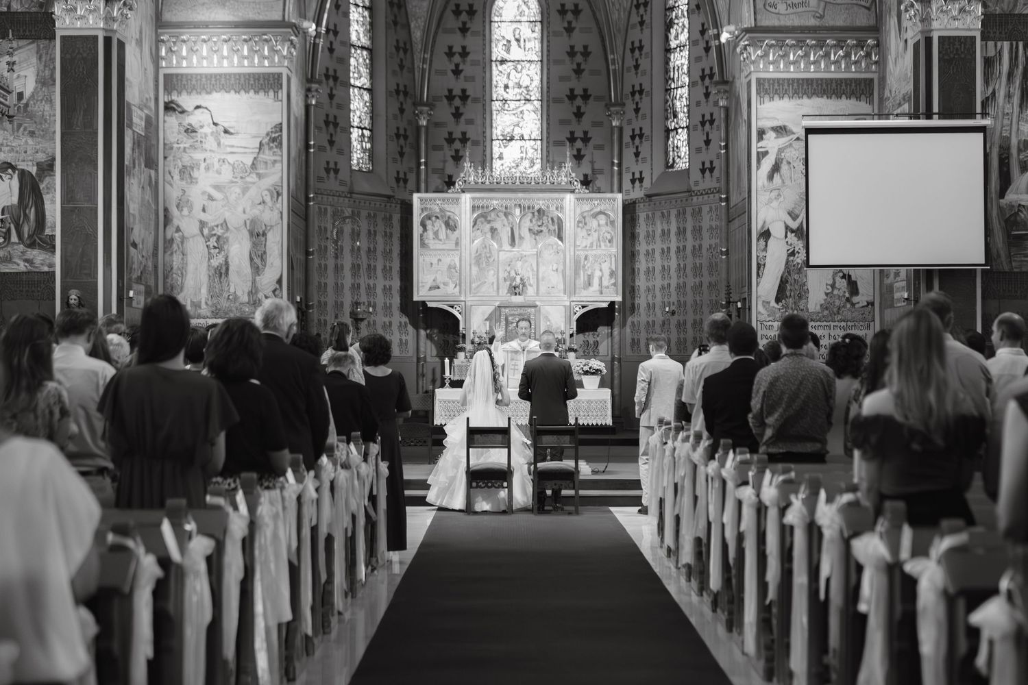 Black and white photograph of a traditional church wedding ceremony with attendees seated in wooden pews.