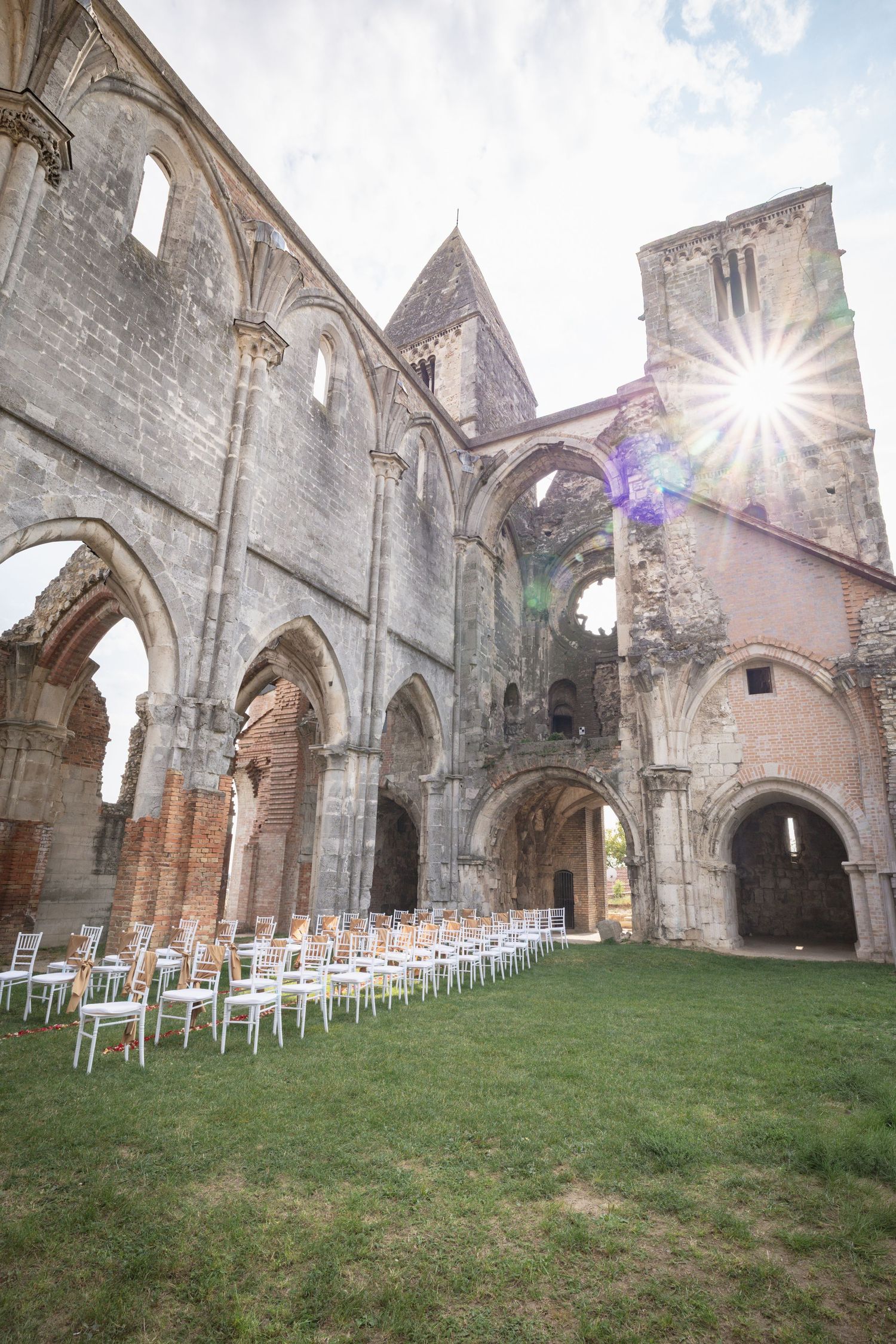 Ancient stone church ruins with gothic arches and white chairs set up for outdoor ceremony.