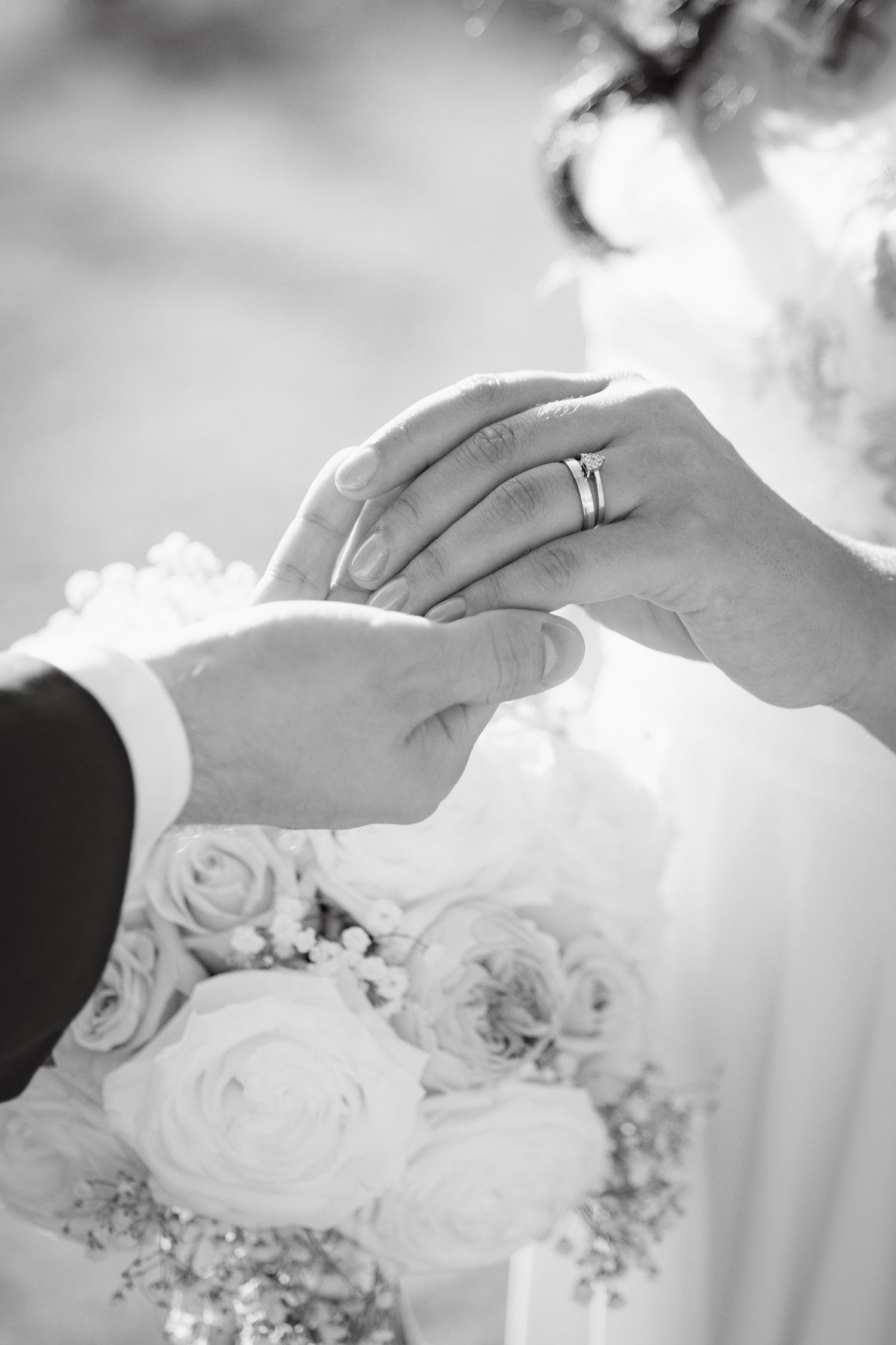 Close-up black and white photos of hands exchanging wedding rings during a ceremony.